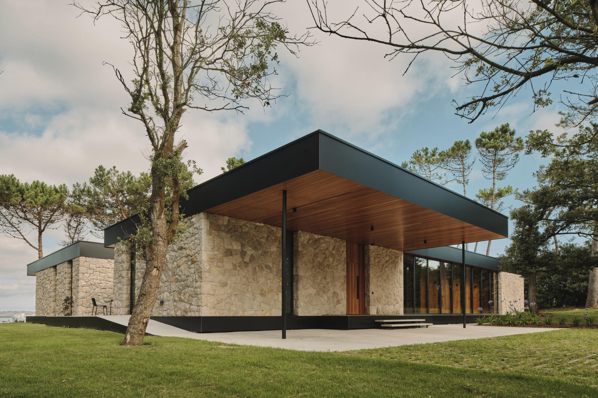 This modern home has limestone walls and large glass panels that form a rhythm of solid and void, while wood adds a sense of warmth.