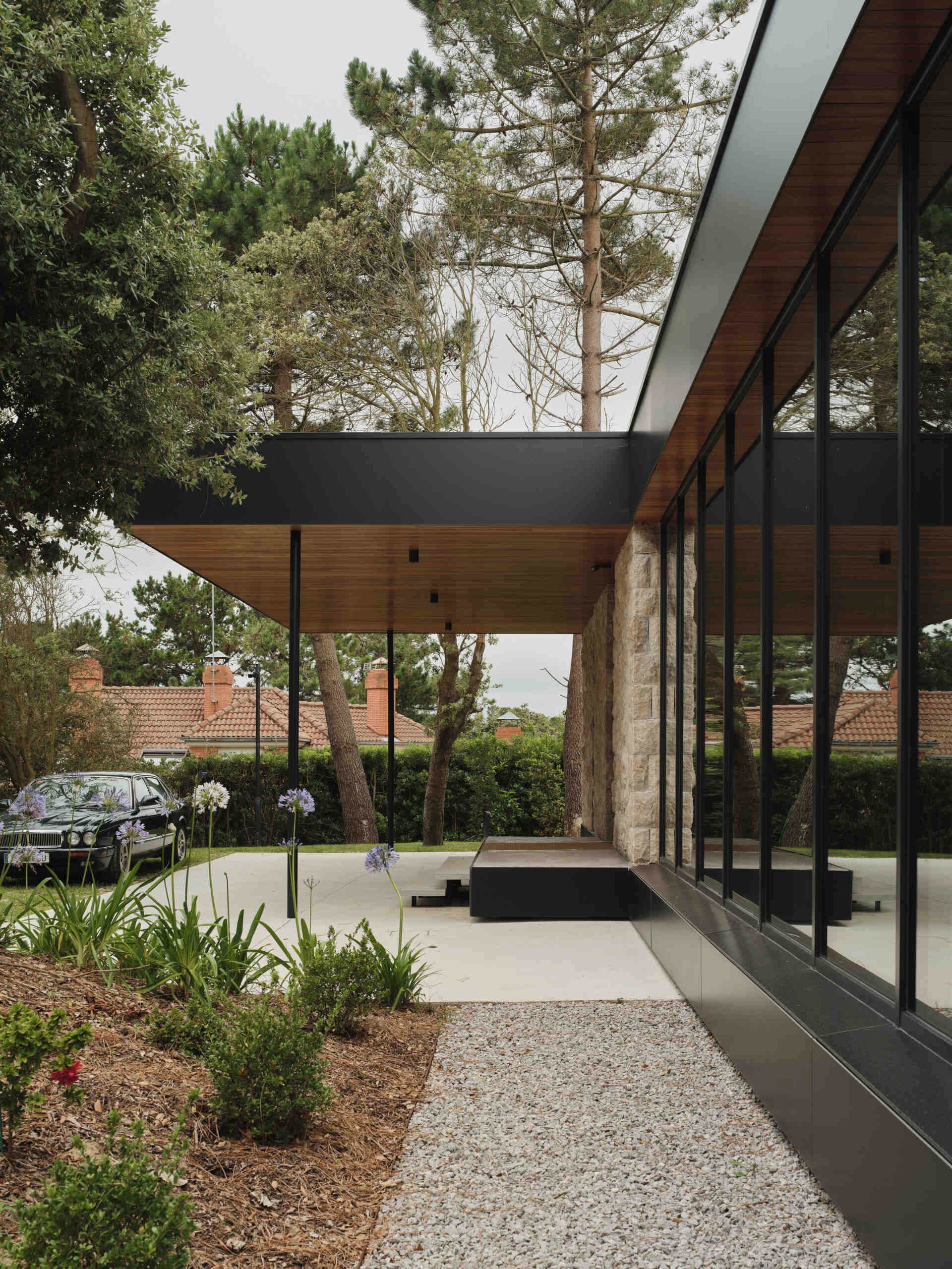 This modern home has limestone walls and large glass panels that form a rhythm of solid and void, while wood adds a sense of warmth.