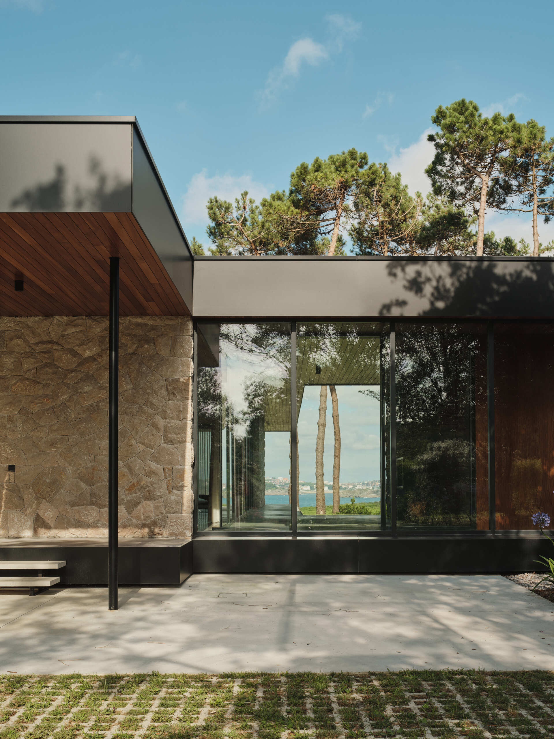 This modern home has limestone walls and large glass panels that form a rhythm of solid and void, while wood adds a sense of warmth.