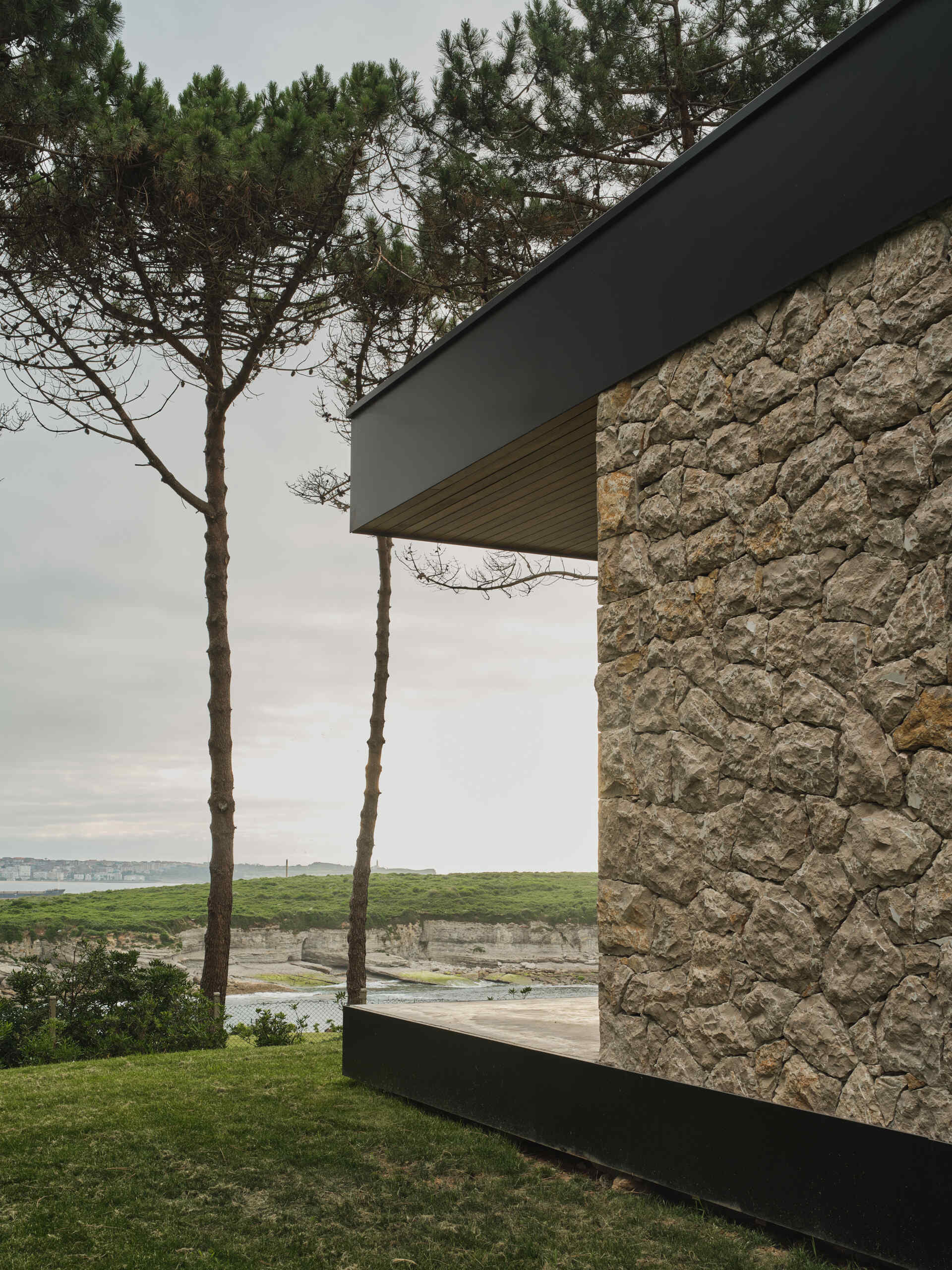 A cast-in-place concrete deck wraps around the home, slightly elevated from the lawn to create a seamless extension of the interior living space. Its smooth surface edge reflect the home's minimalist language while providing a durable platform for enjoying the surrounding landscape.