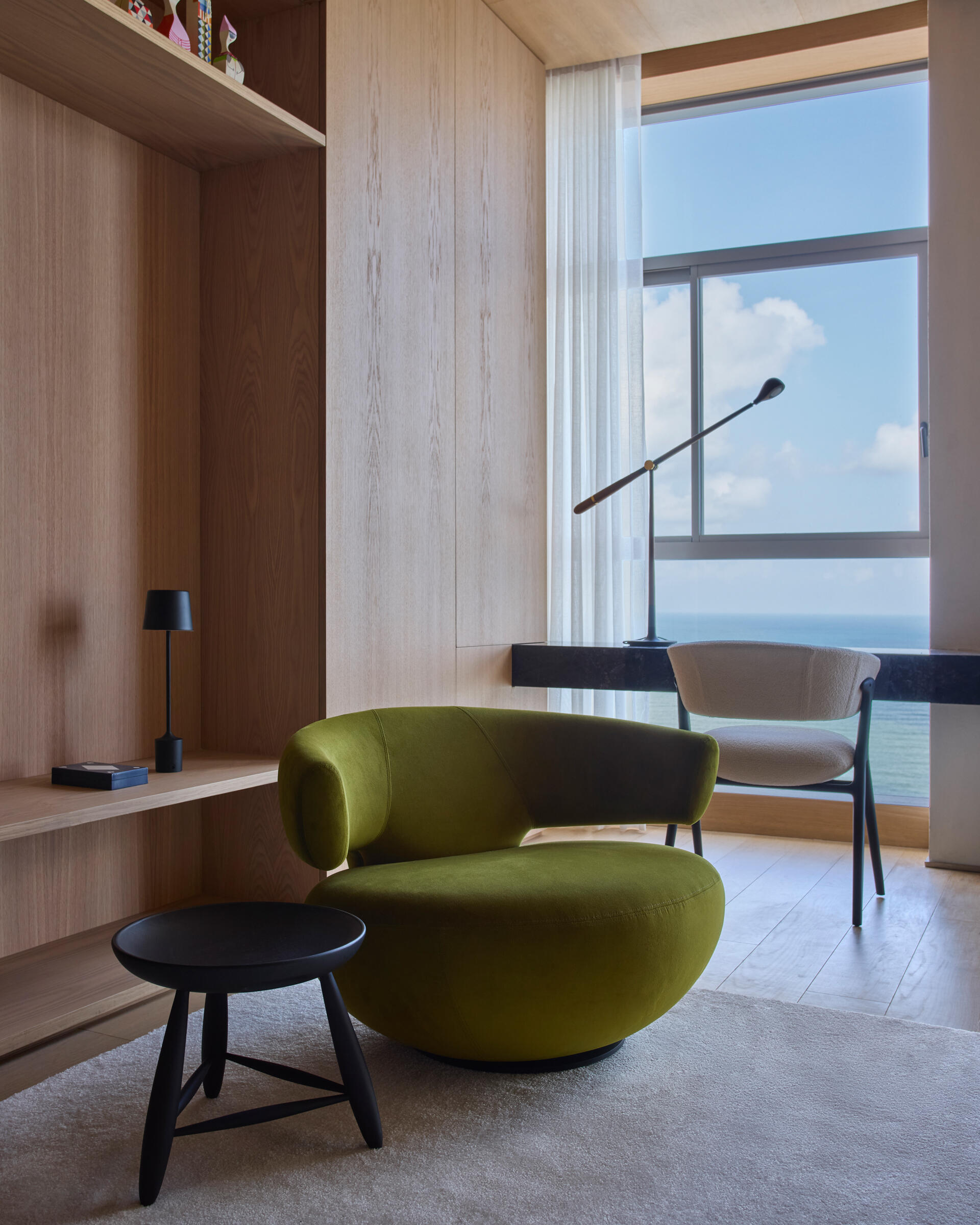 This modern TV room is located on the lower floor, along with the bedrooms and bathrooms. Natural wood cabinetry brings warmth to the TV room, supporting the calm atmosphere of the private level, while a desk runs along the wall facing out towards the views.