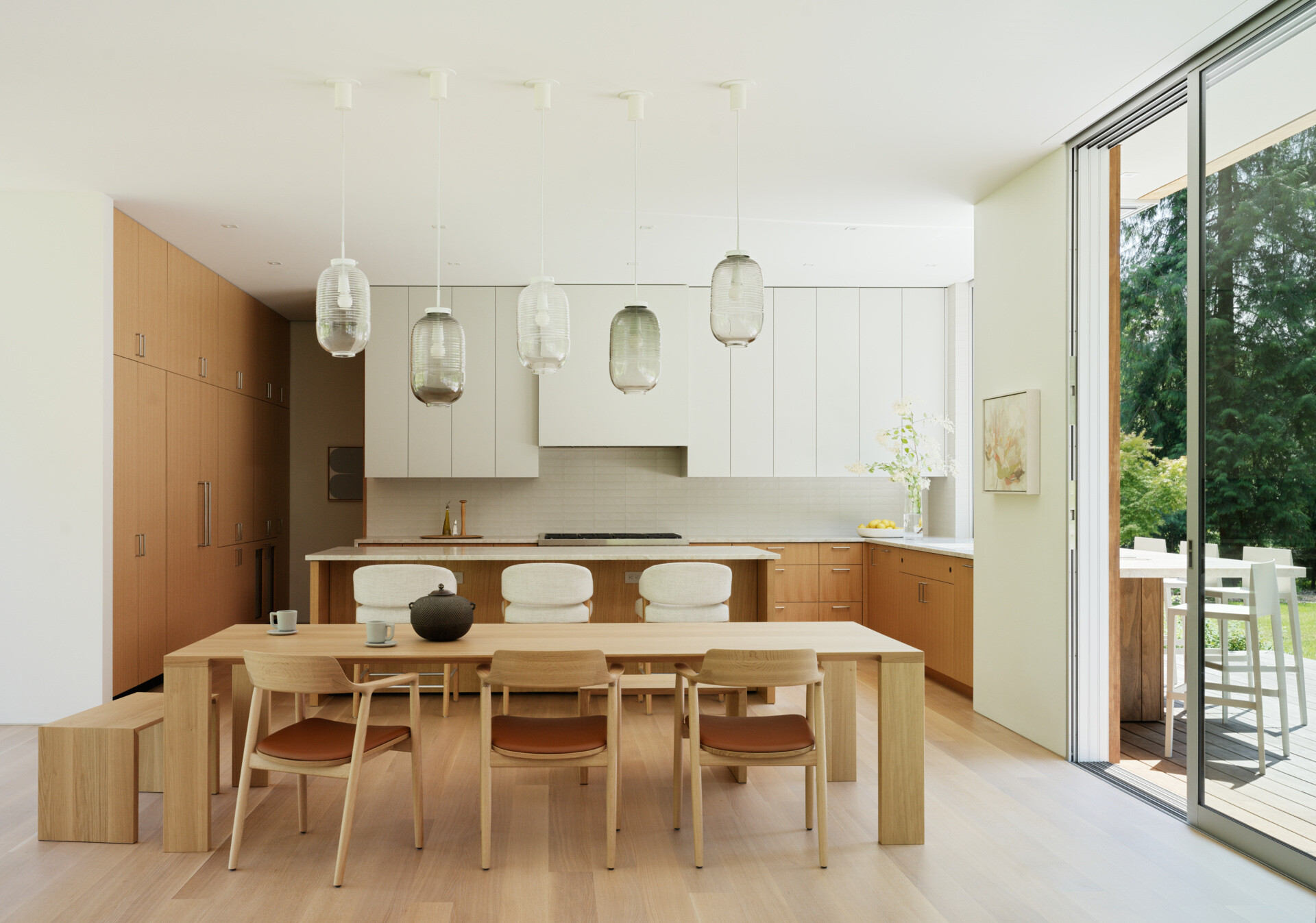 The kitchen is designed for daily use and family gatherings alike. A neutral palette of light-toned wood,  and matte finishes creates a feeling of calm utility. Open sightlines to the rest of the living wing keep the space connected, while durable surfaces and practical layouts support a busy lifestyle. 