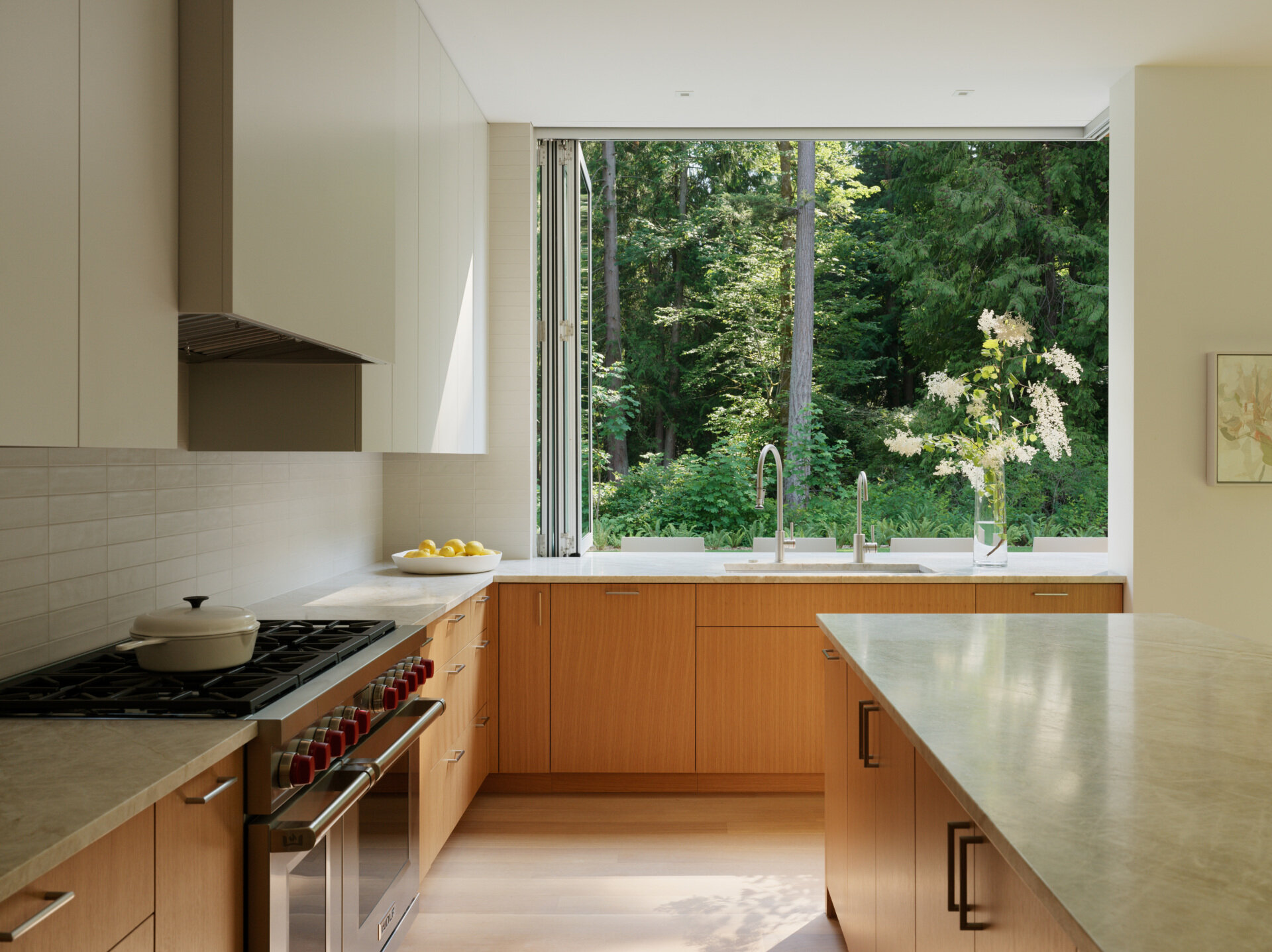 The kitchen is designed for daily use and family gatherings alike. A neutral palette of light-toned wood,  and matte finishes creates a feeling of calm utility. Open sightlines to the rest of the living wing keep the space connected, while durable surfaces and practical layouts support a busy lifestyle. 