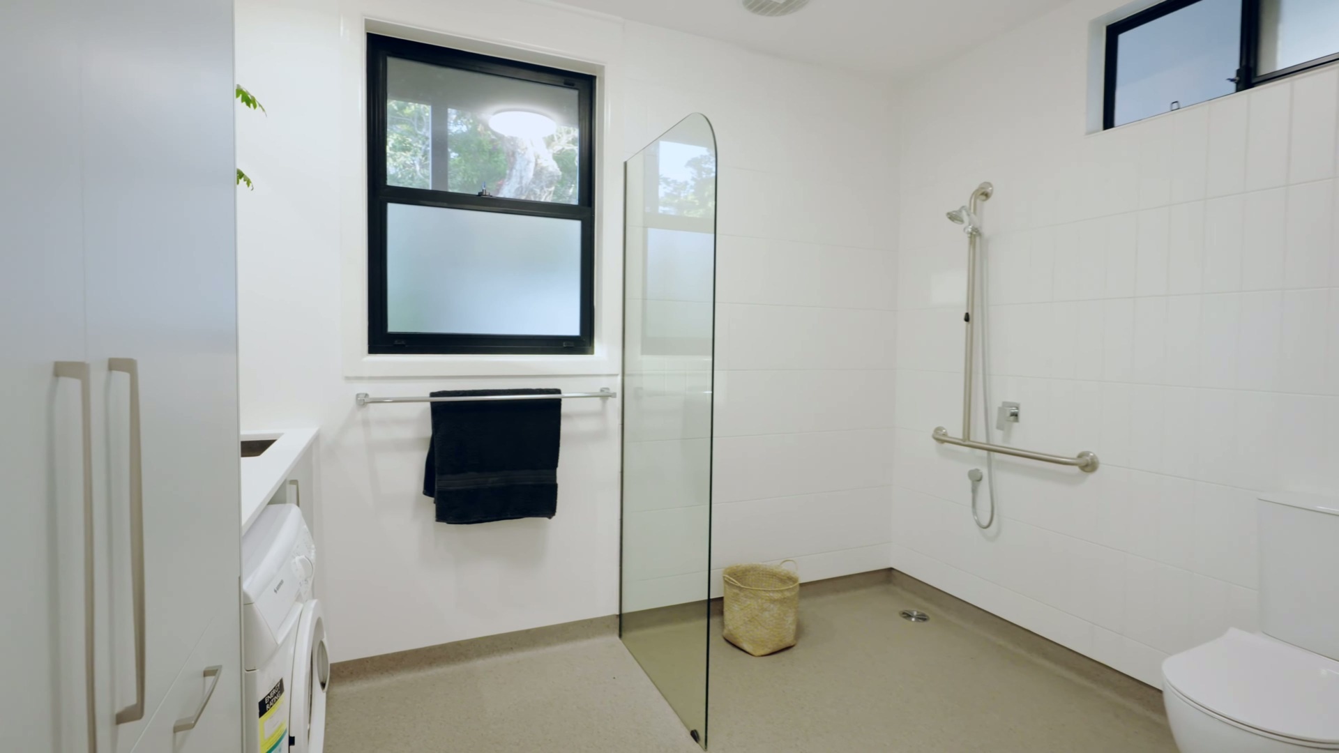 A spacious, accessible bathroom and laundry room with a wet-room shower and plenty of storage.
