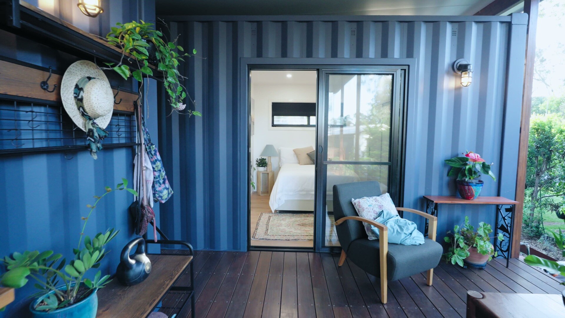 A quiet, efficient bedroom in a container home has with a full-height wardrobe with overhead storage, and a built-in desk designed for working from home in comfort.