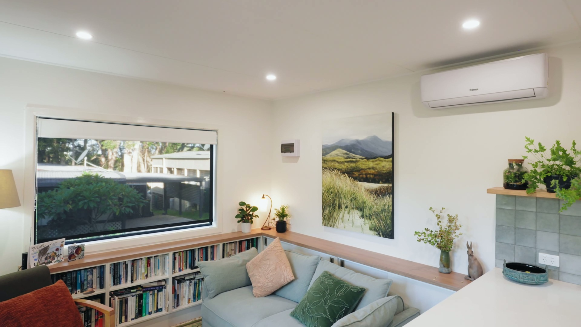 A light-filled living space with built-in book storage, hidden cabinetry, and a clean, plastered finish that brings warmth and functionality together.