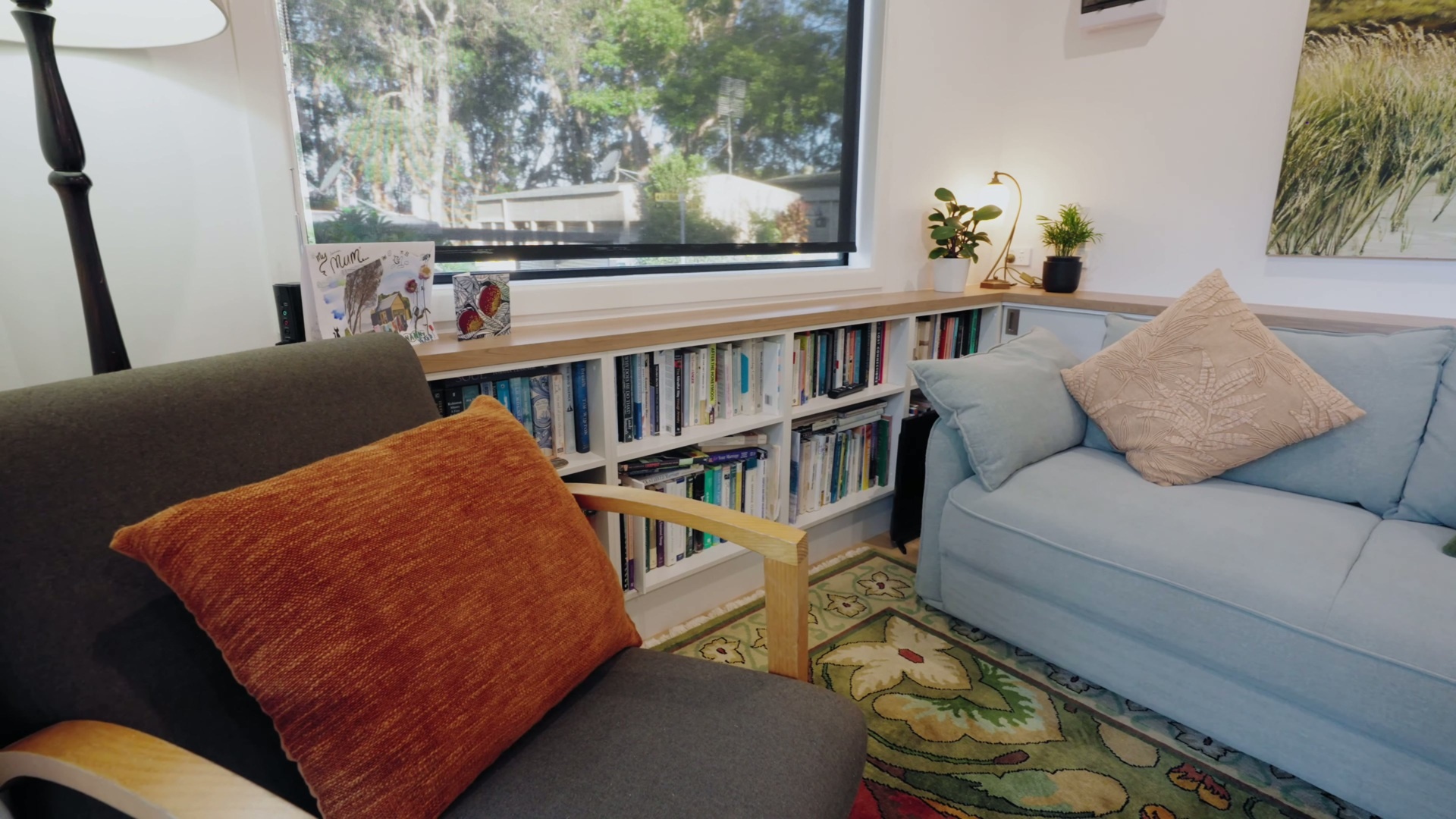 A light-filled living space with built-in book storage, hidden cabinetry, and a clean, plastered finish that brings warmth and functionality together.