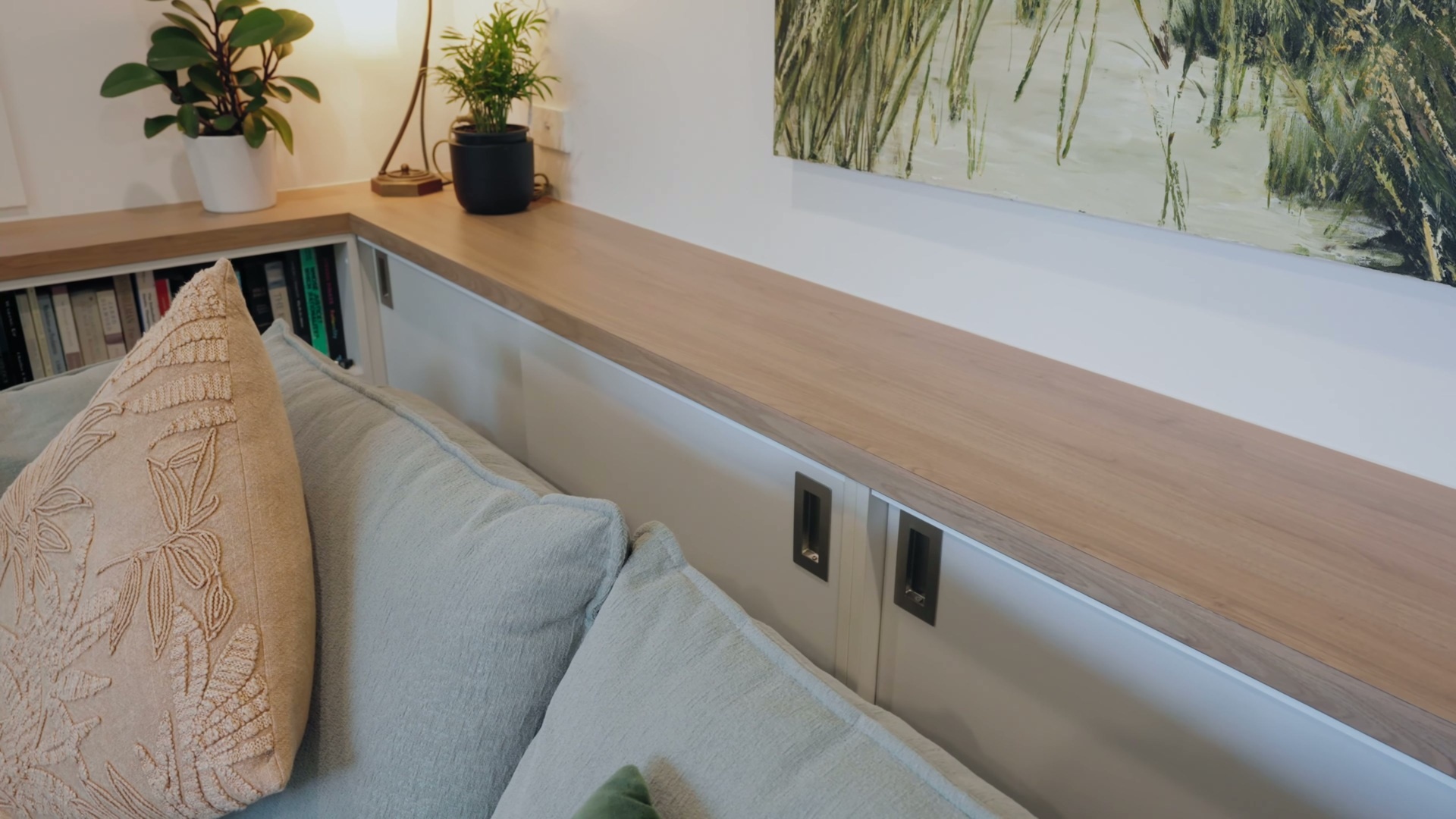 A light-filled living space with built-in book storage, hidden cabinetry, and a clean, plastered finish that brings warmth and functionality together.