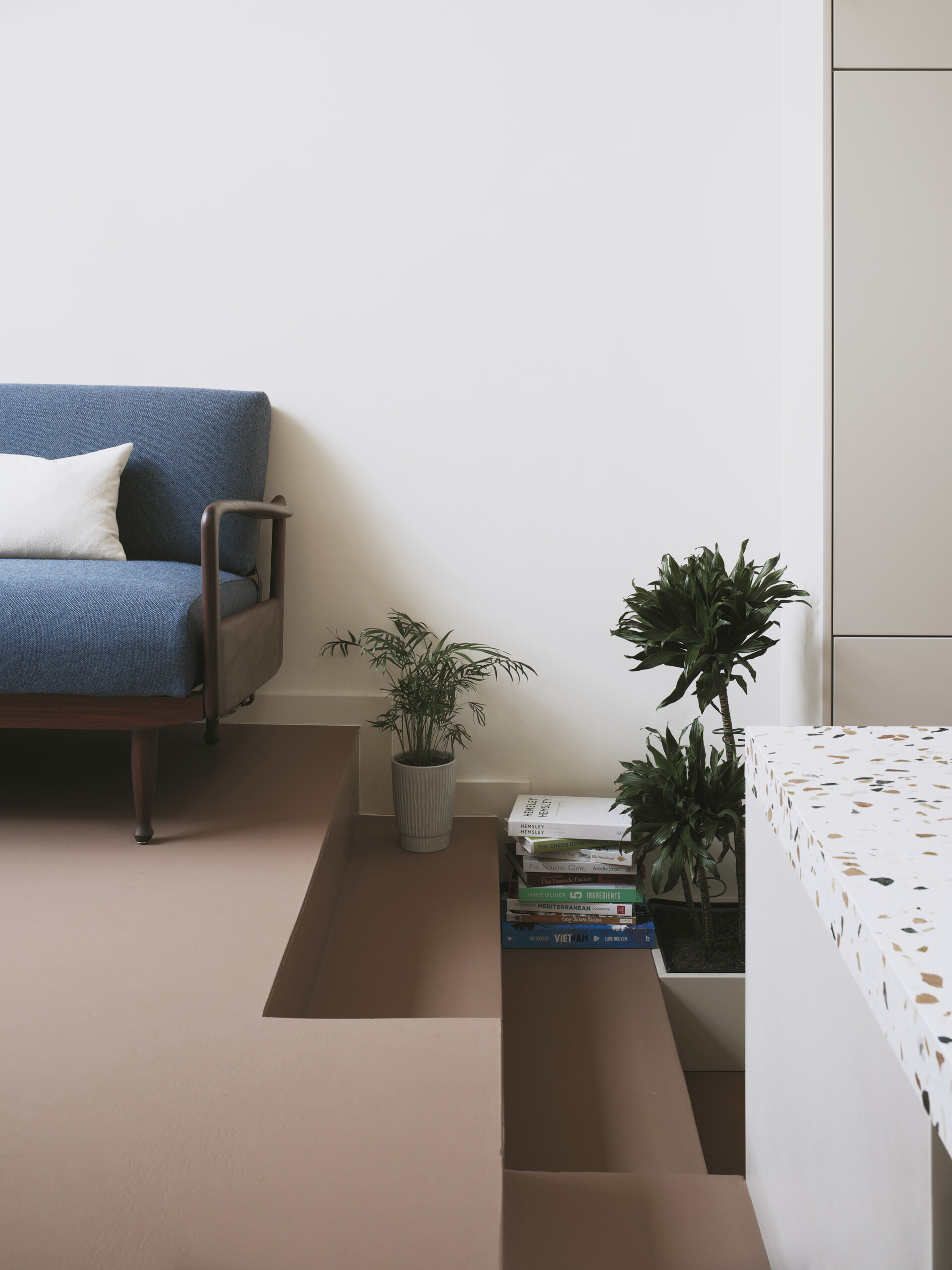 The kitchen and dining areas of this home are arranged across different levels, with a short set of steps subtly marking the transition between the two. This change in height gives each zone its own identity while maintaining a visual connection.