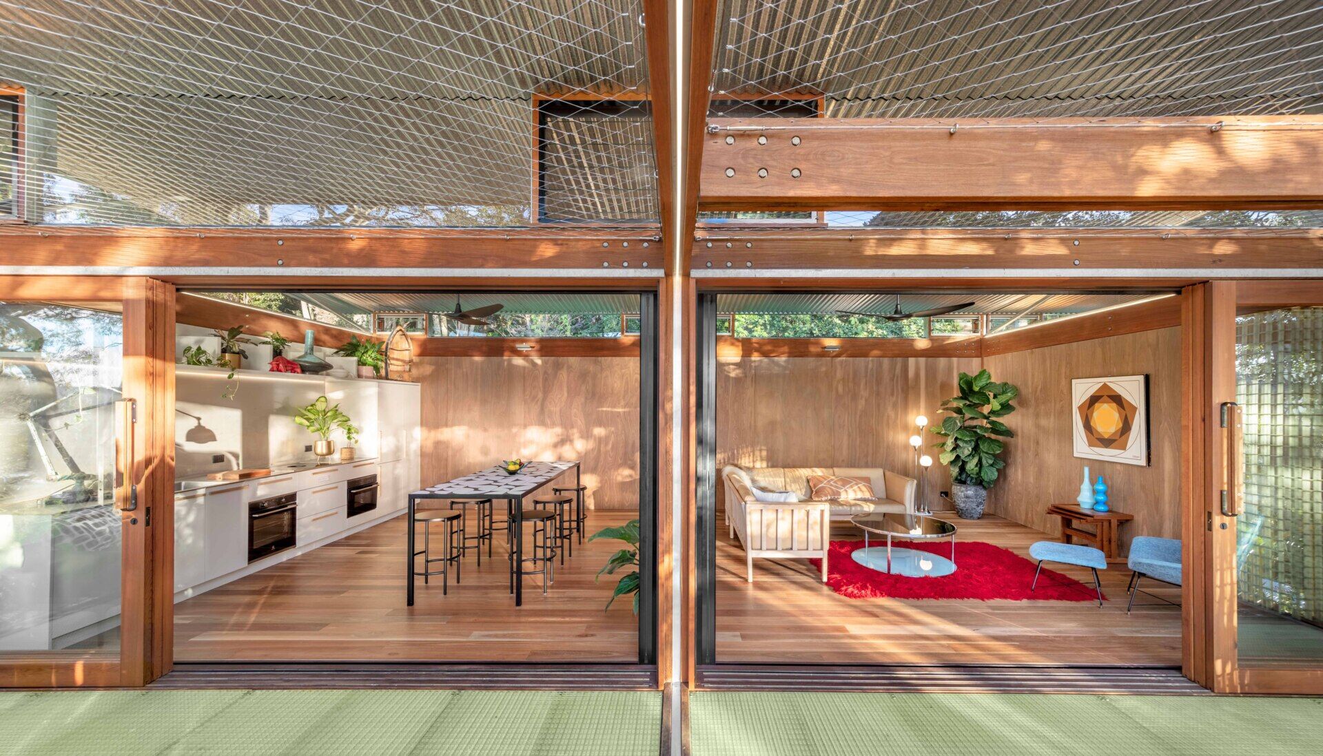 Sliding doors and louvred windows invite soft light and fresh air into this relaxed open plan living, dining, and kitchen space.
