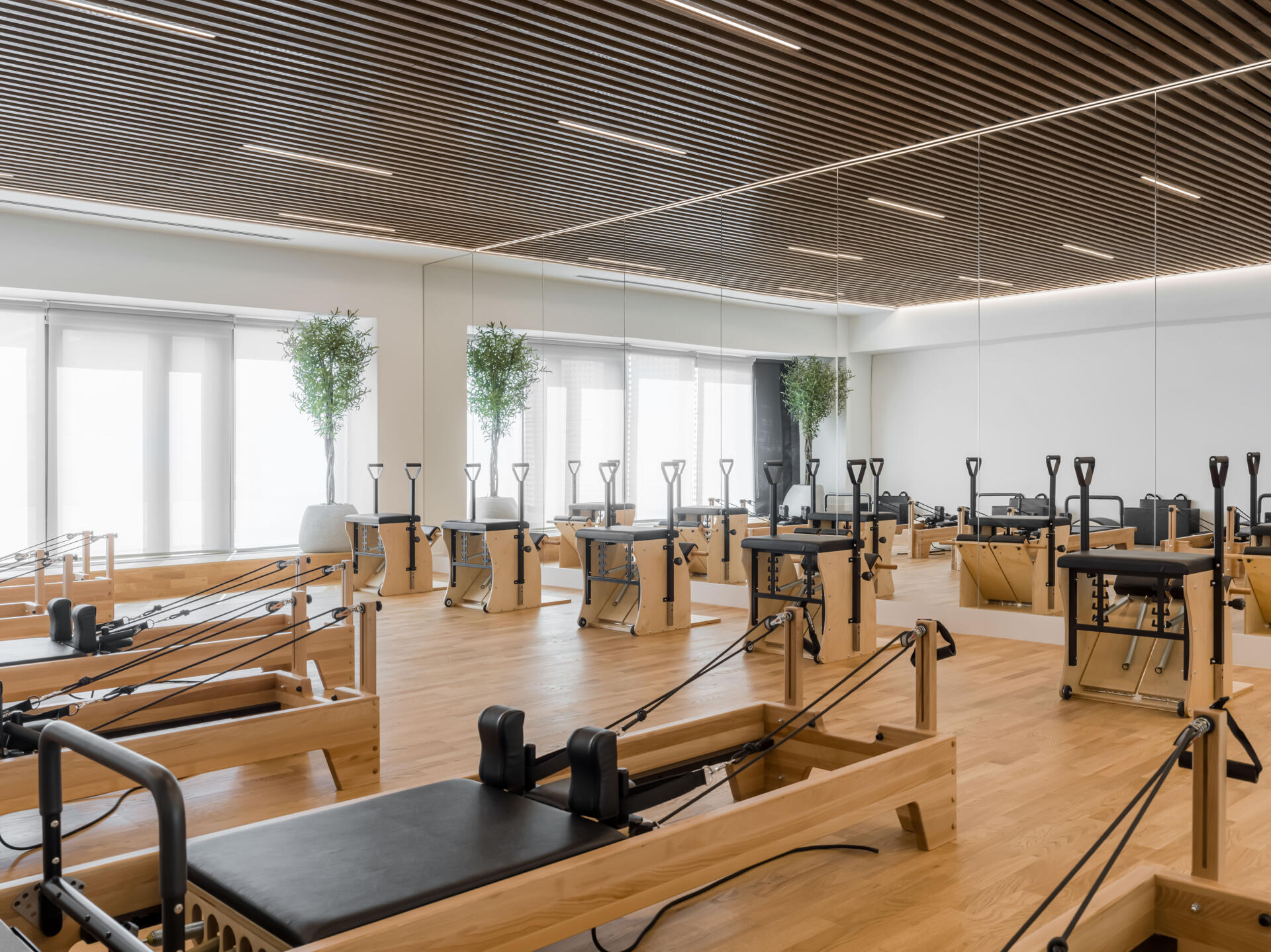 The second floor of SIAM SPA takes on a more minimalist mood with smooth grey walls, veined wood accents, and lush greenery. Custom wooden fitness equipment blends beauty with function, offering a serene environment for stretching, strength, and movement.