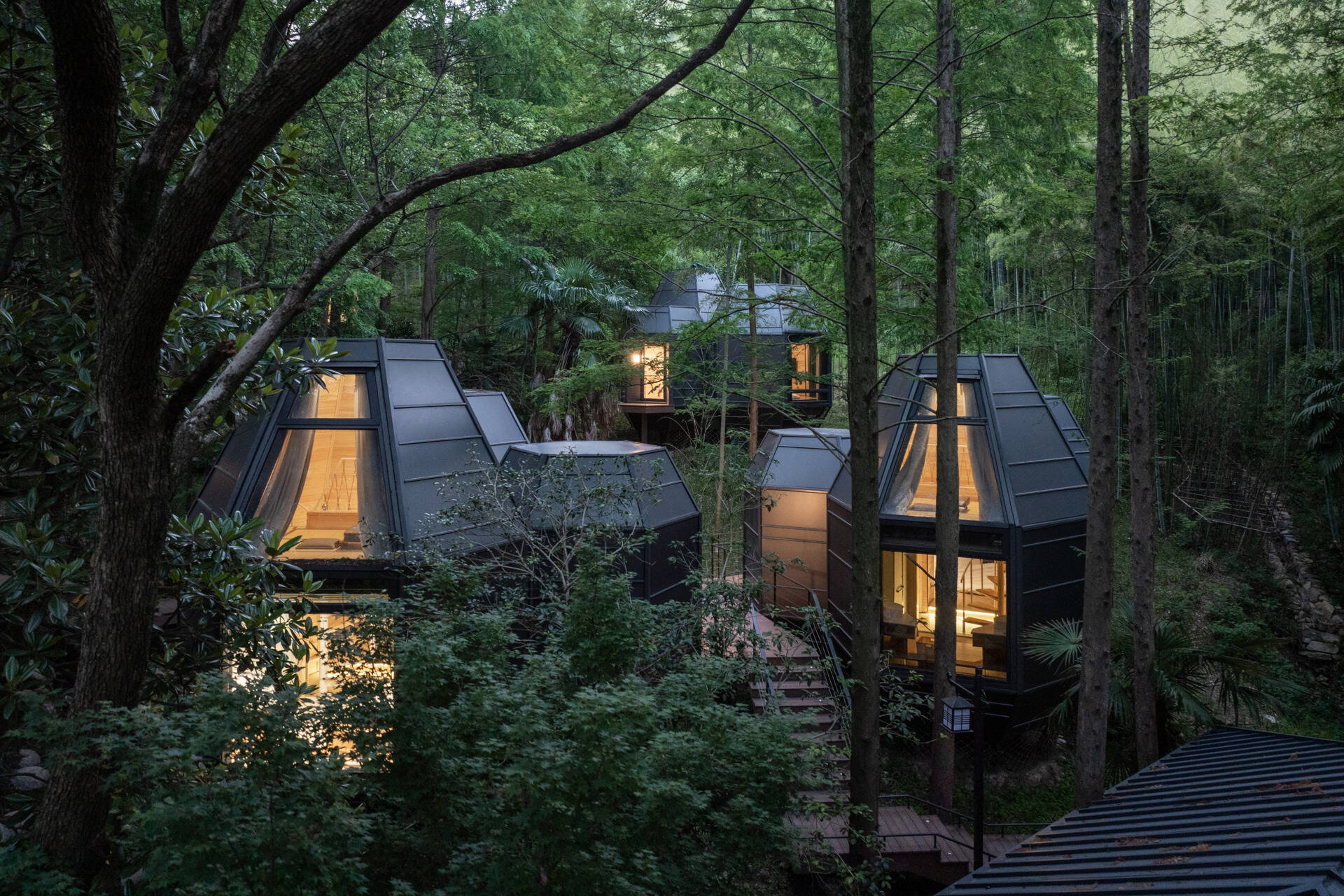 Lightweight and modular, these cabins take cues from pinecones and tree forms. Elevated design preserves the forest floor, while angled rooflines echo the grove’s vertical rhythm.