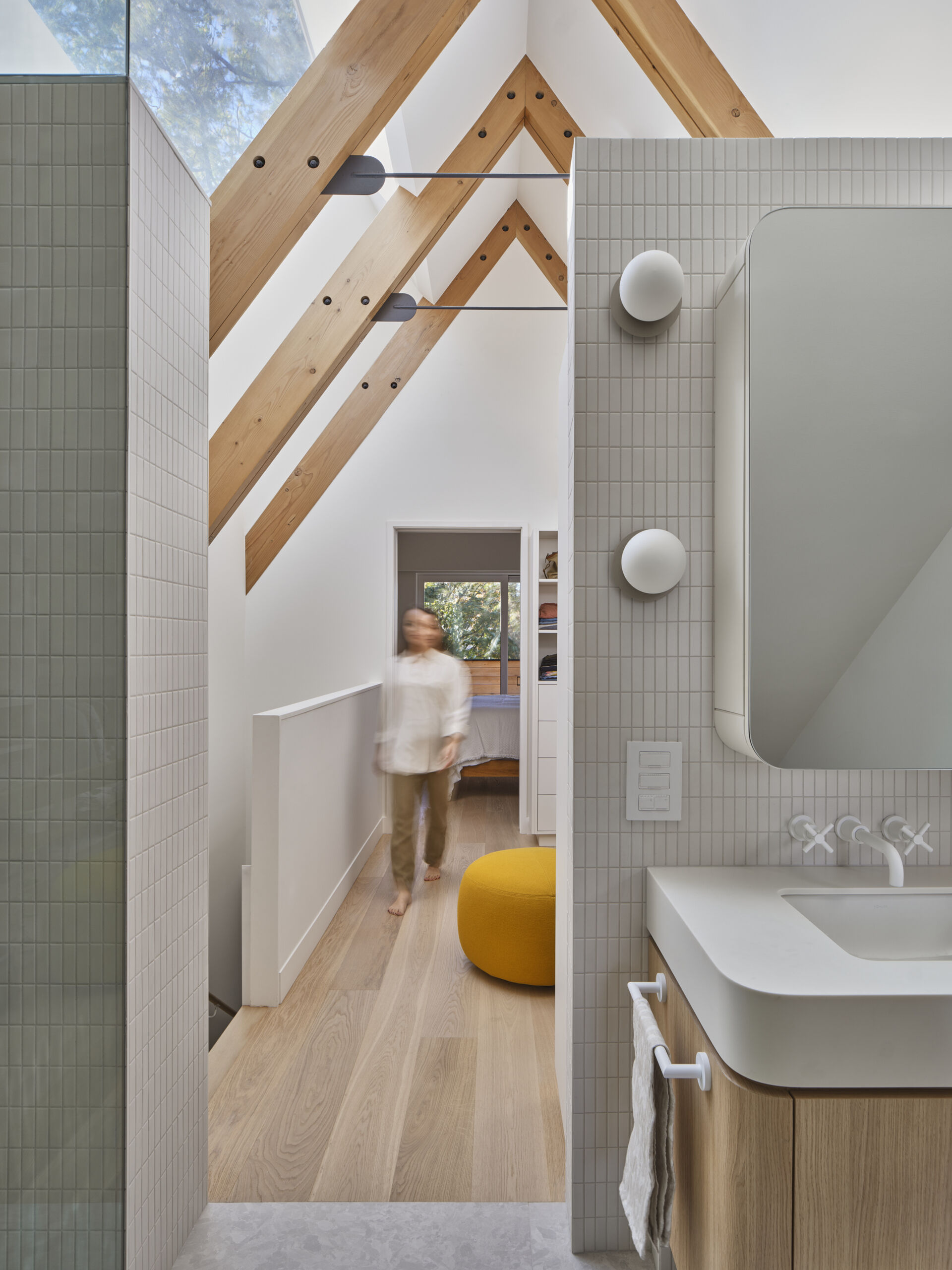 A-frame ceilings, timber beams, and framed views create a tranquil primary bedroom retreat above the trees.