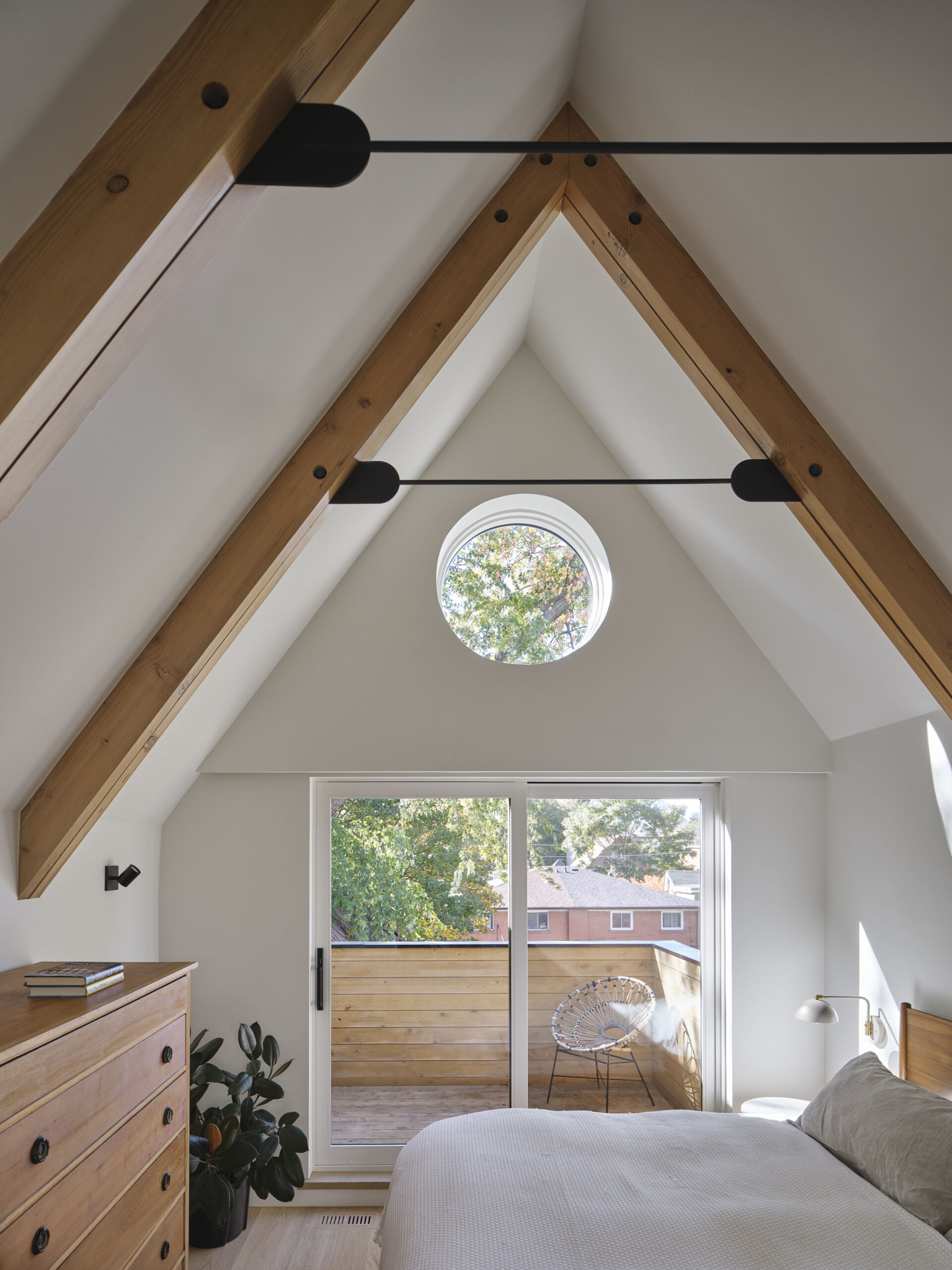 A-frame ceilings, timber beams, and framed views create a tranquil primary bedroom retreat above the trees.