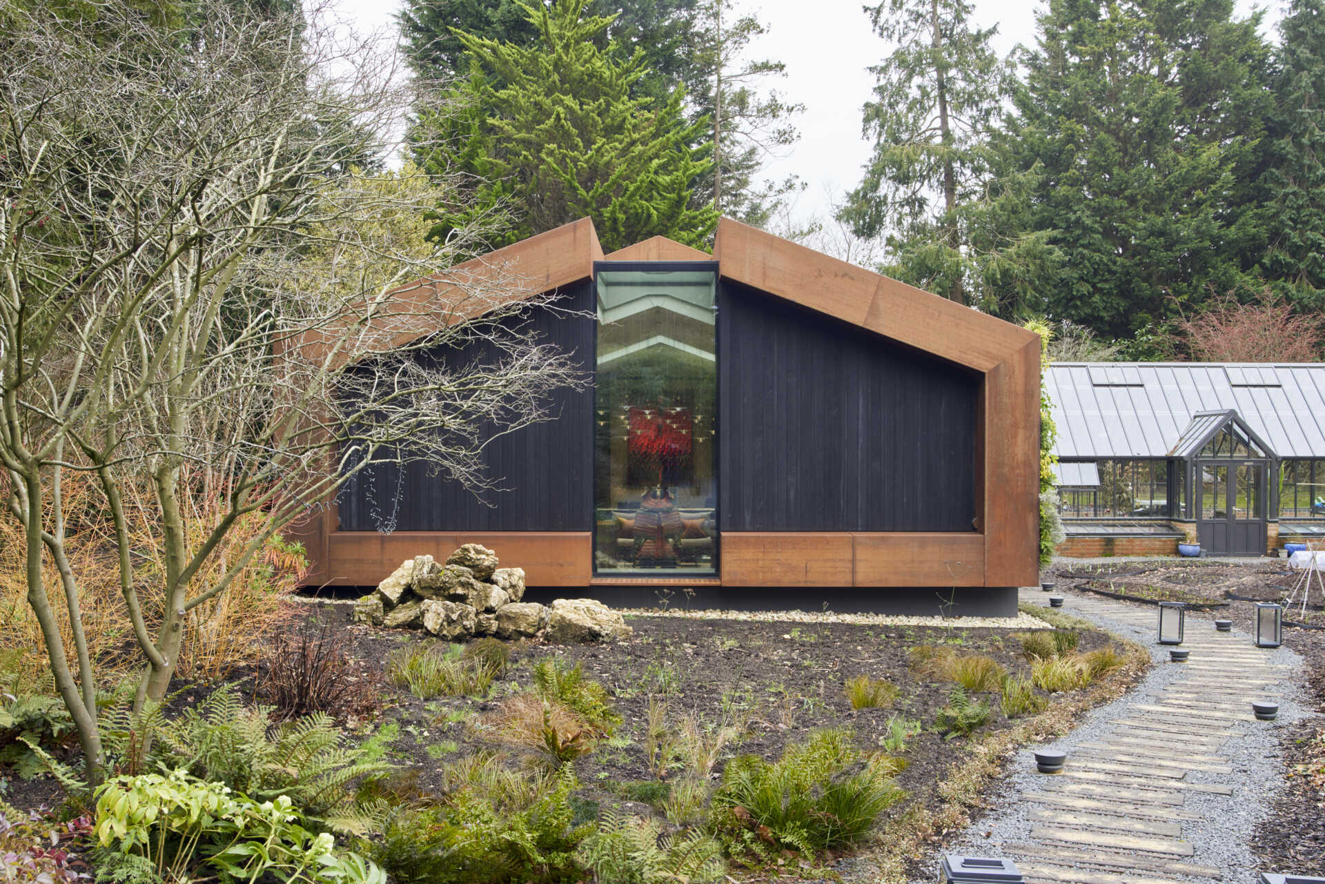 This modern music pavilion blends charred timber, Corten steel, and a living roof to create a sculptural retreat in the landscape.