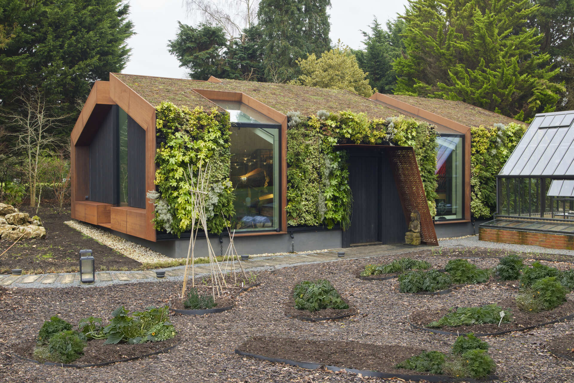 This modern music pavilion blends charred timber, Corten steel, and a living roof to create a sculptural retreat in the landscape.