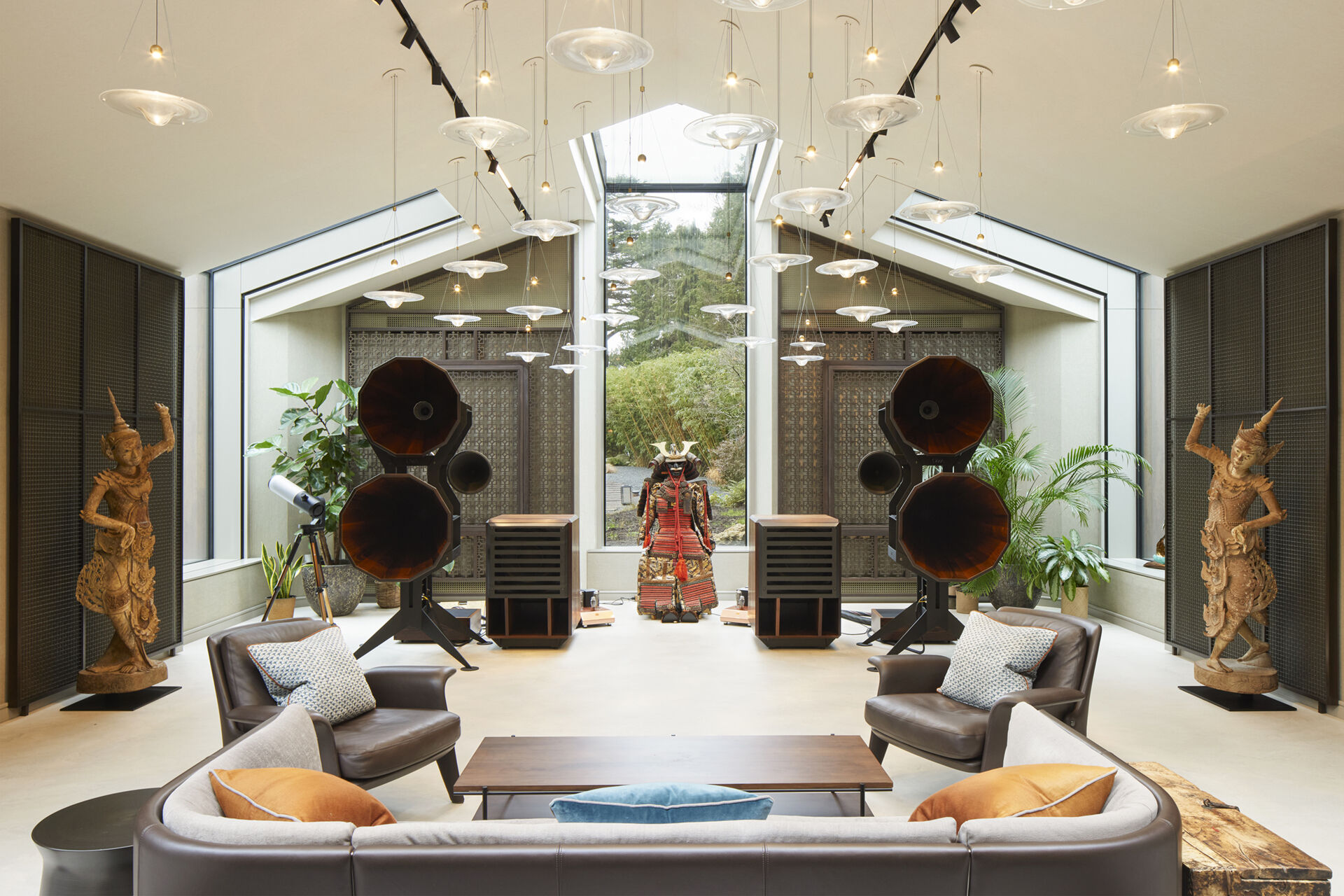 The interior of this modern music pavilion is a refined blend of sound-focused design and artful display, featuring custom joinery, soft lighting, and a cascading glass pendant that reflects like ripples across the minimalist micro cement floor.