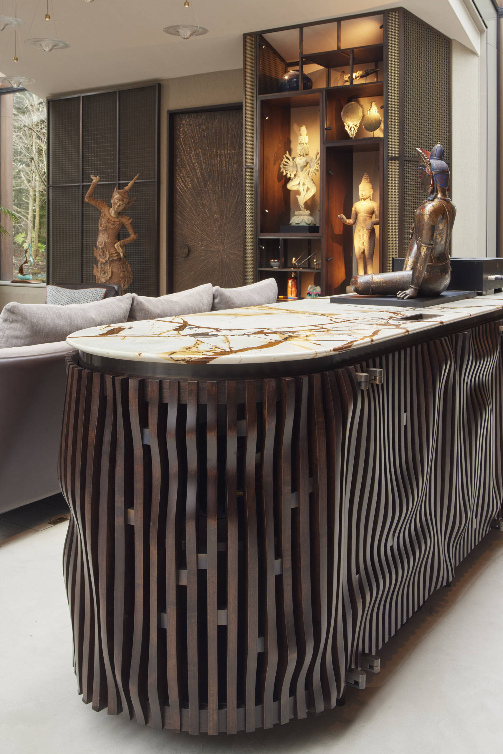 The interior of this modern music pavilion is a refined blend of sound-focused design and artful display, featuring custom joinery, soft lighting, and a cascading glass pendant that reflects like ripples across the minimalist micro cement floor.