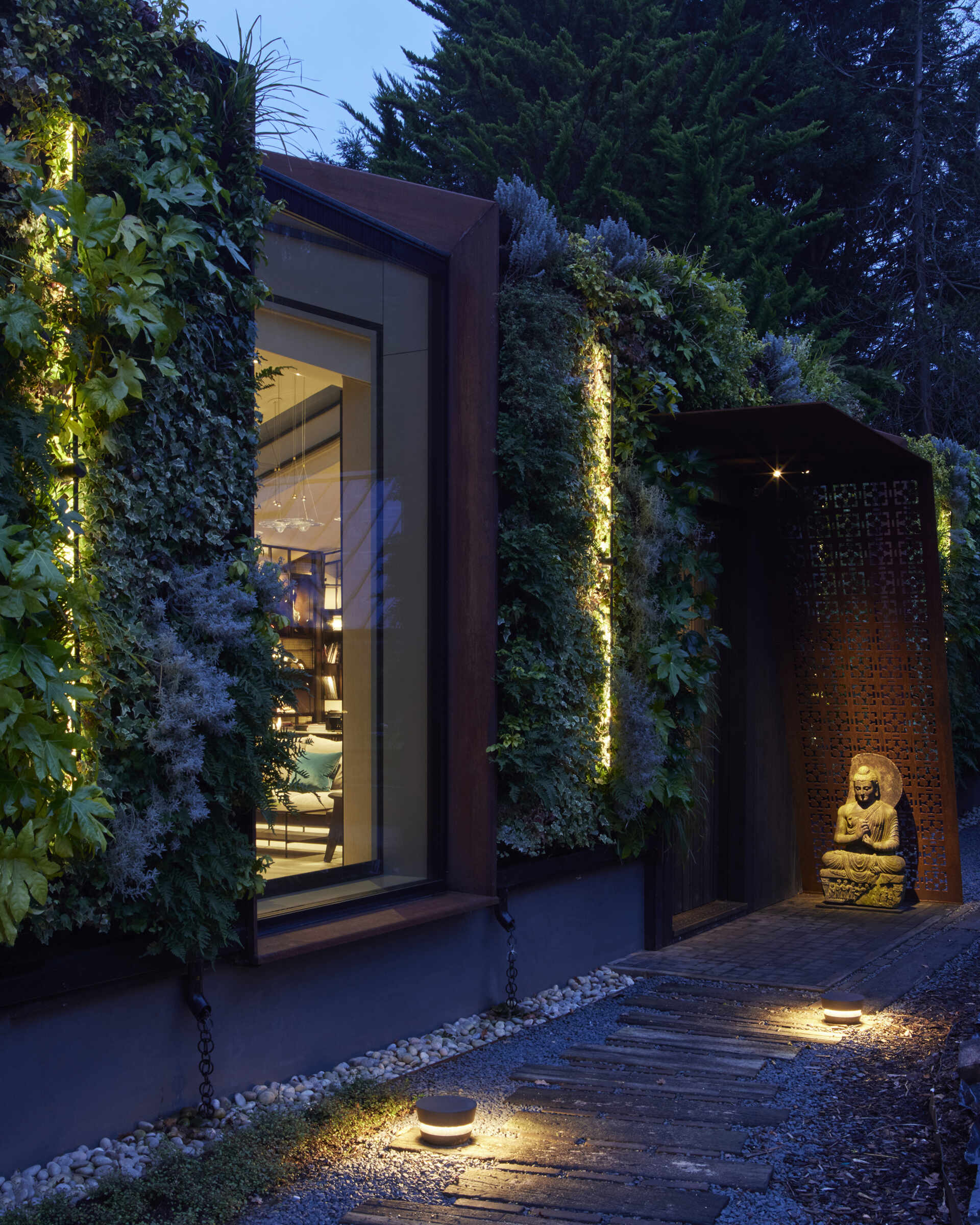 This modern music pavilion blends charred timber, Corten steel, and a living roof to create a sculptural retreat in the landscape. At night, subtle lighting brings the textures to life, softly illuminating its bold architectural form.