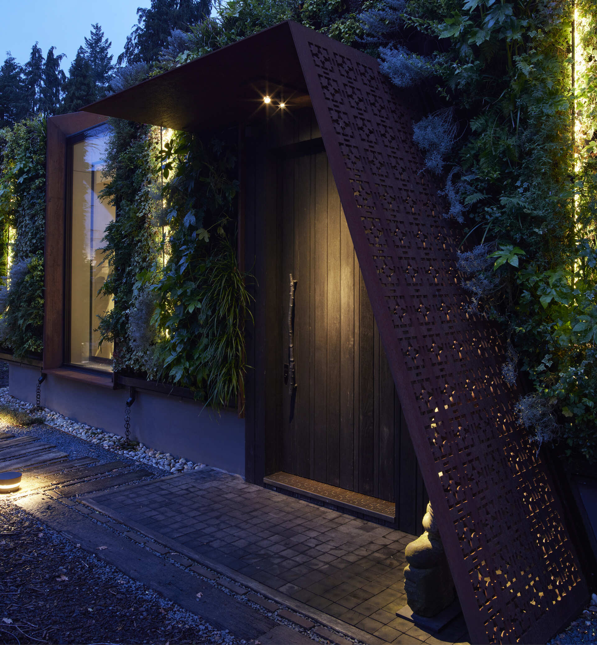 This modern music pavilion blends charred timber, Corten steel, and a living roof to create a sculptural retreat in the landscape. At night, subtle lighting brings the textures to life, softly illuminating its bold architectural form.