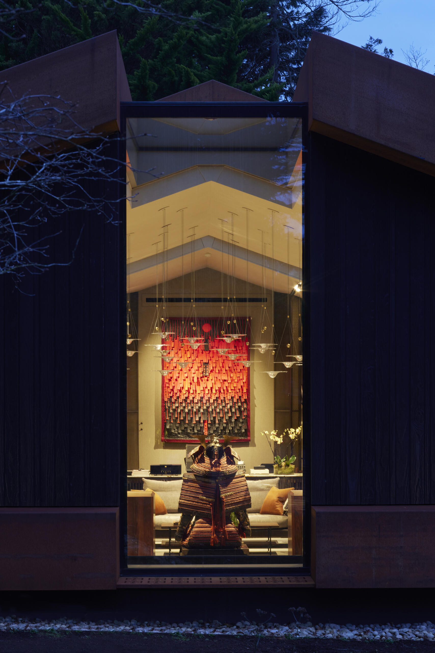 This modern music pavilion blends charred timber, Corten steel, and a living roof to create a sculptural retreat in the landscape. At night, subtle lighting brings the textures to life, softly illuminating its bold architectural form.