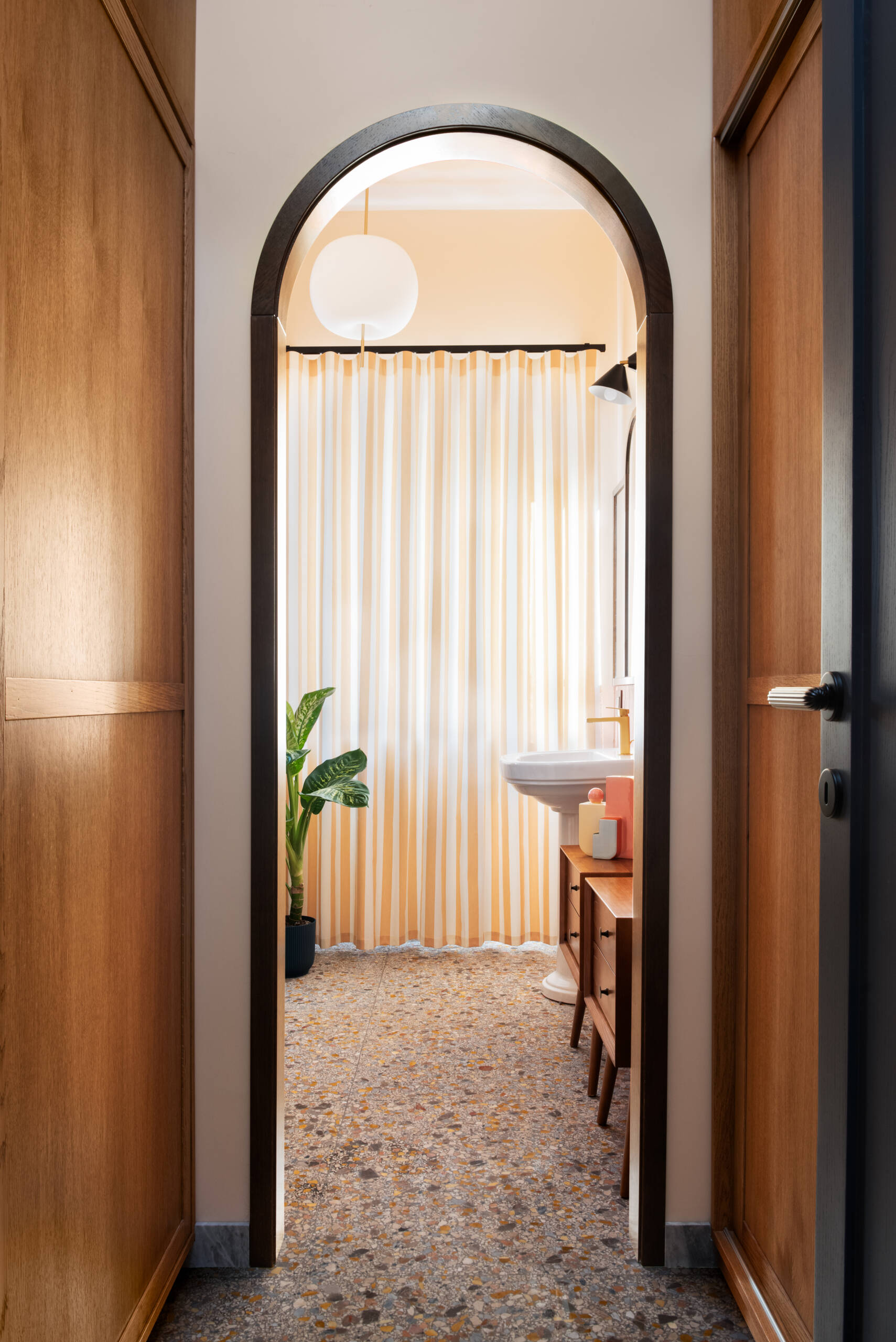 Preceded by a compact laundry zone hidden behind sliding oak wardrobes, this guest bathroom leans into the warmth of its materials. Rust-colored tiles, peach walls, and brass accents evoke a nostalgic nod to the home’s 1960s origin, softened into something cozy and romantic.