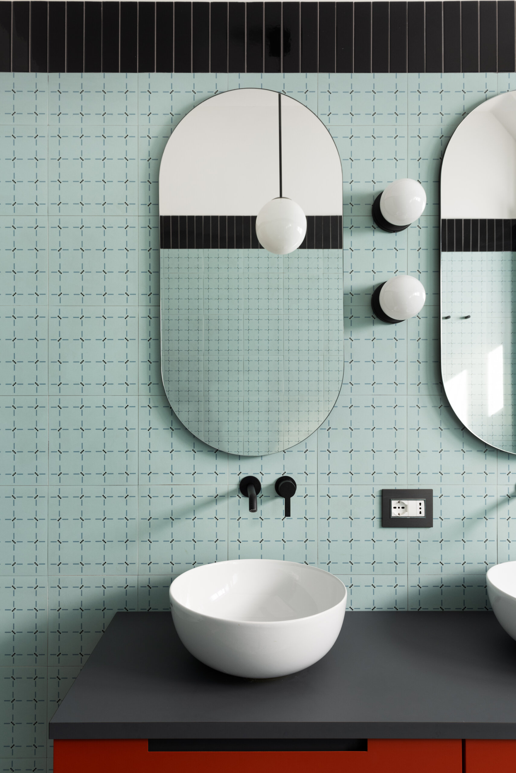 The main bathroom in this renovated 1960s apartment has large format t “Ghiara Minuta Mix” marble-look tiles by Marazzi, while the walls are clad in “Confetti” tiles by Ceramica Vogue in the Torino pattern. Black accents tie all of the design decisions together.