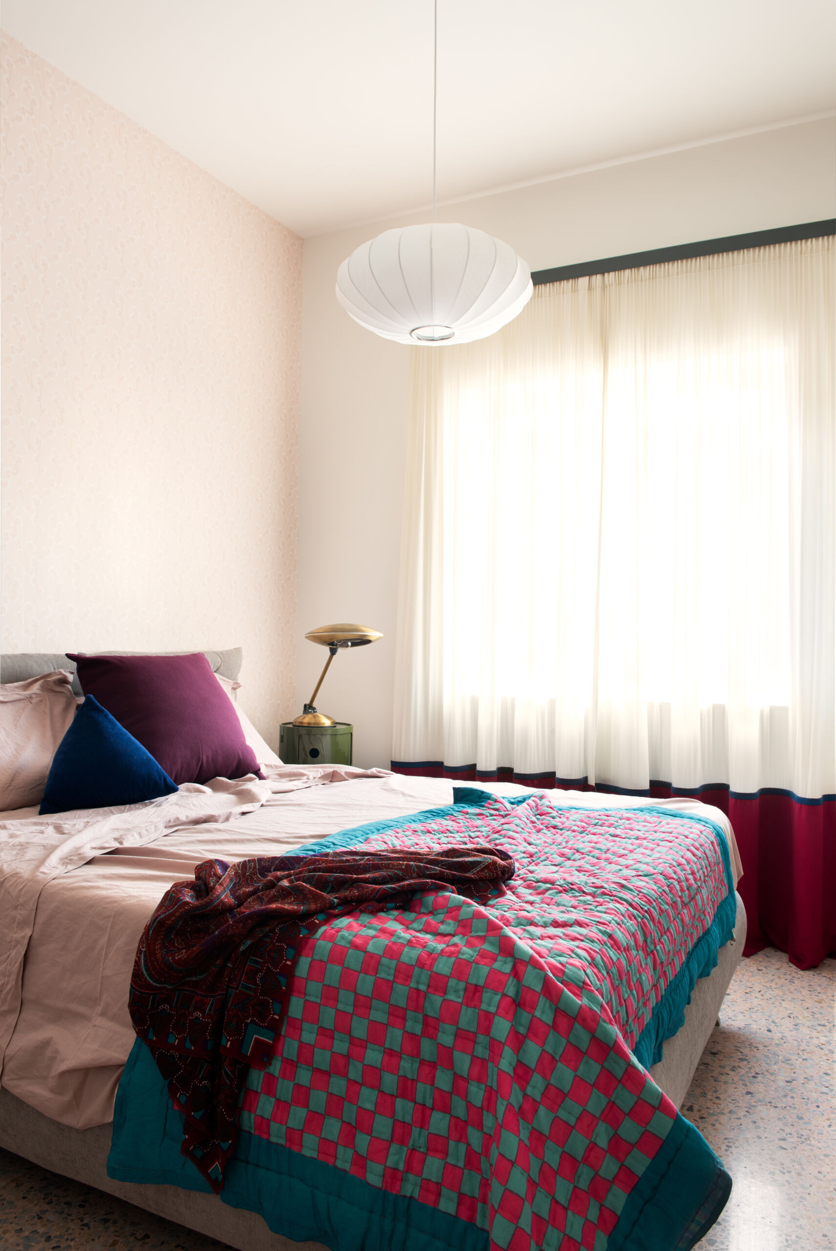 The bedroom in this 1960s apartment renovation has the terrazzo floors and custom curtains.