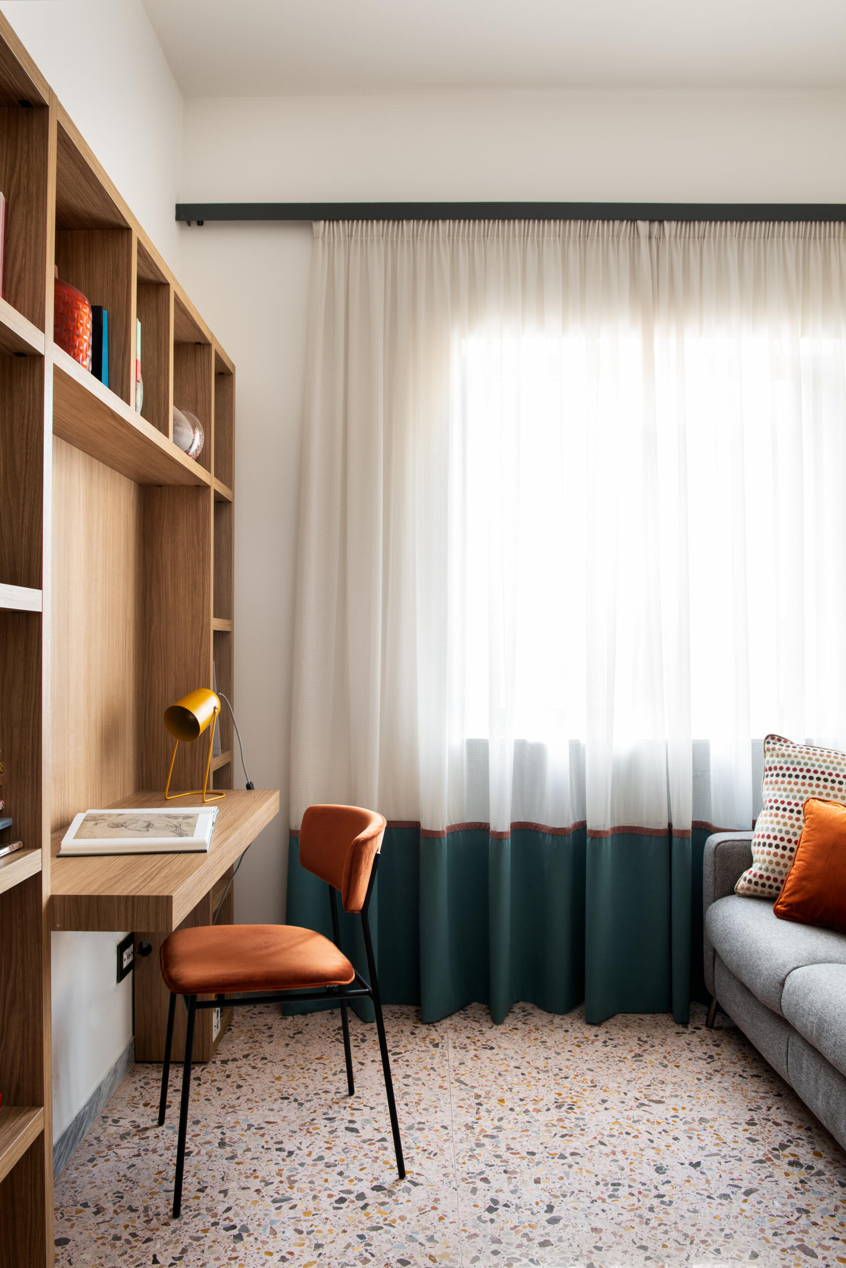 A calm, focused workspace sits within the private wing of this updated 1960s apartment in Rome, blending minimal design with soft textures and a custom bookcase with built-in desk.
