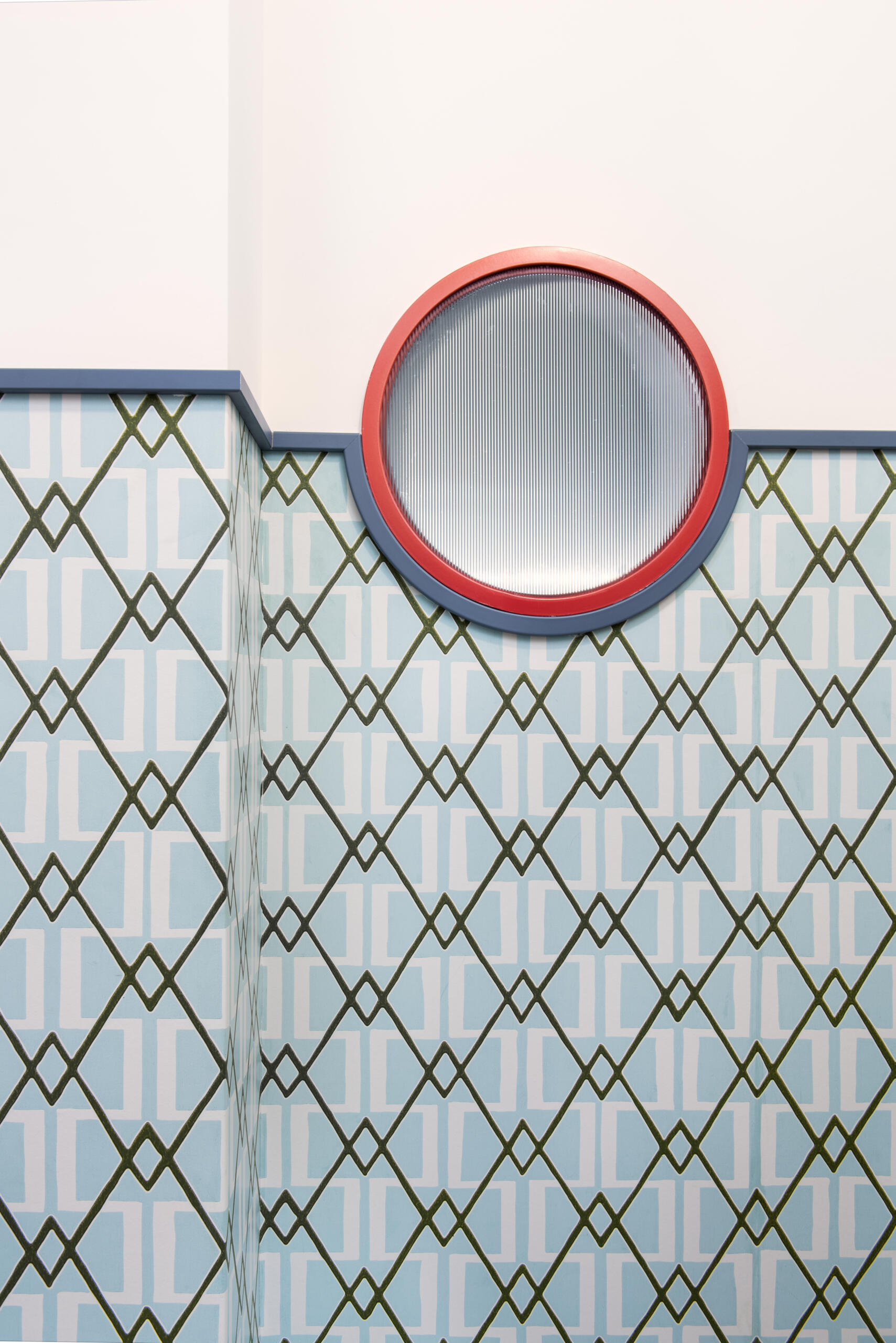 In this renovated 1960s apartment, the entryway pairs bold boiserie with lacquer-red glass doors that visually anchor the space.
