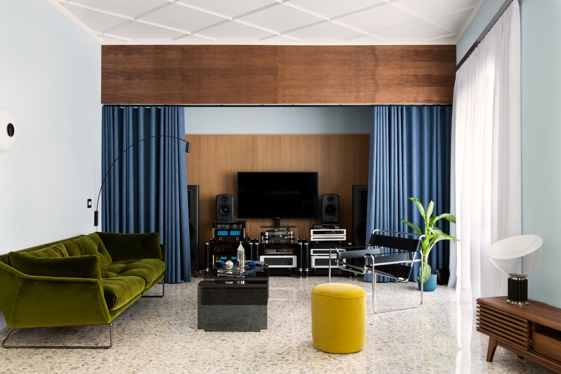 This 1960s apartment renovation features a living room with sculptural plaster ceilings, terrazzo floors, and a sound system hidden behind curtains.