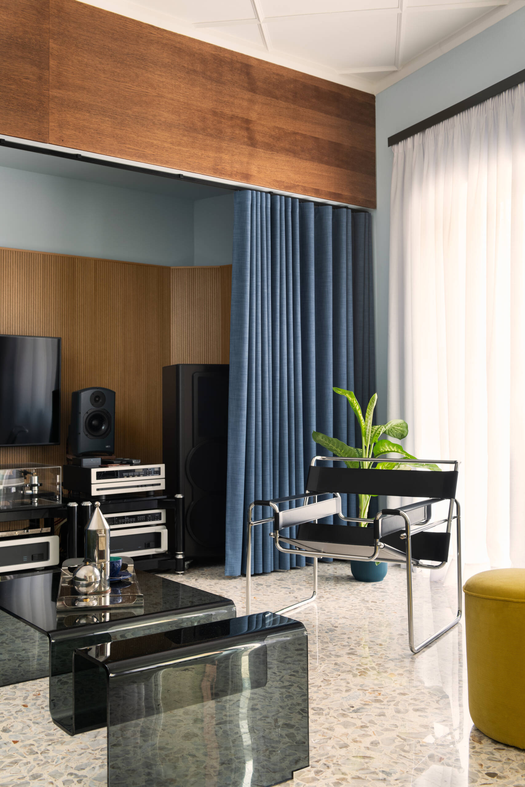 This 1960s apartment renovation features a living room with sculptural plaster ceilings, terrazzo floors, and a sound system hidden behind curtains.