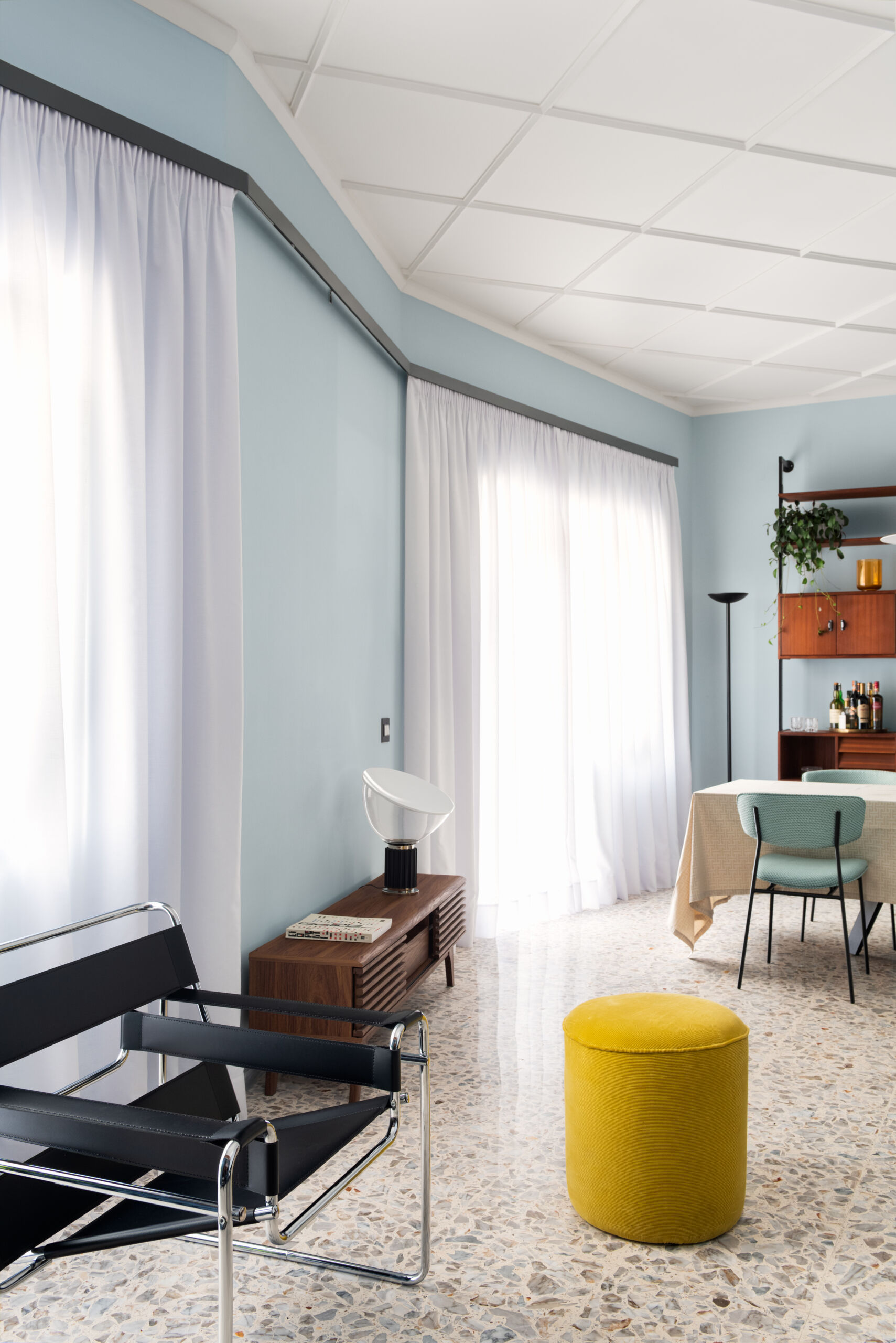 This 1960s apartment renovation features a living room with sculptural plaster ceilings, terrazzo floors, and a sound system hidden behind curtains.