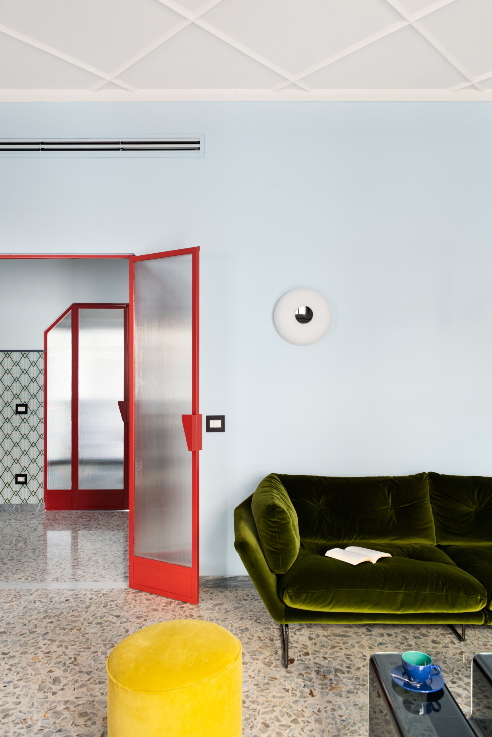 This 1960s apartment renovation features a living room with sculptural plaster ceilings, terrazzo floors, and a sound system hidden behind curtains.