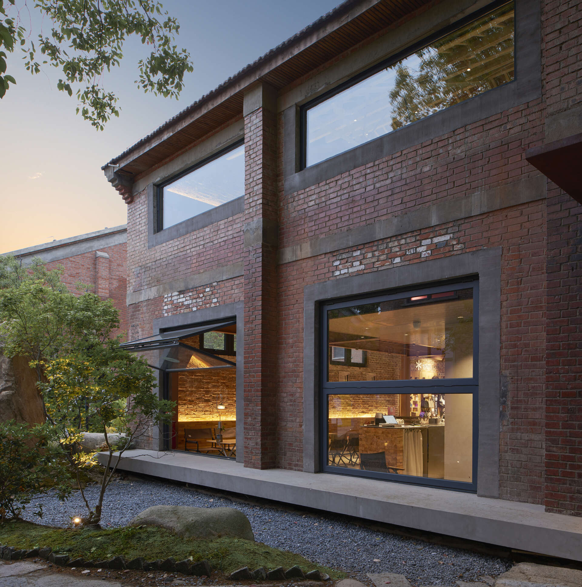 An original 1950s red-brick warehouse was renovated into a modern cafe with two levels.