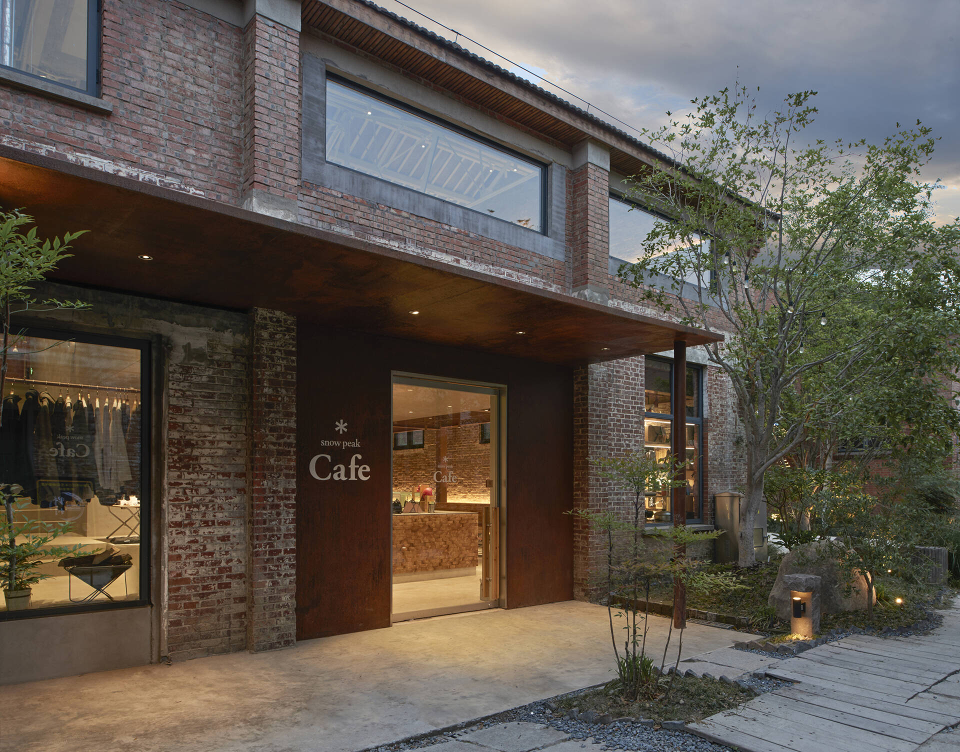 The entrance to this modern cafe in a renovated warehouse is simple and understated, with no bold signage or decorative elements, just a clean frame of weathered steel that lets the materials speak for themselves.