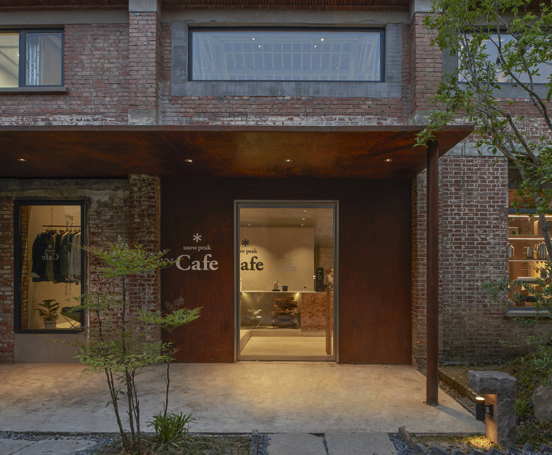 The entrance to this modern cafe in a renovated warehouse is simple and understated, with no bold signage or decorative elements, just a clean frame of weathered steel that lets the materials speak for themselves.