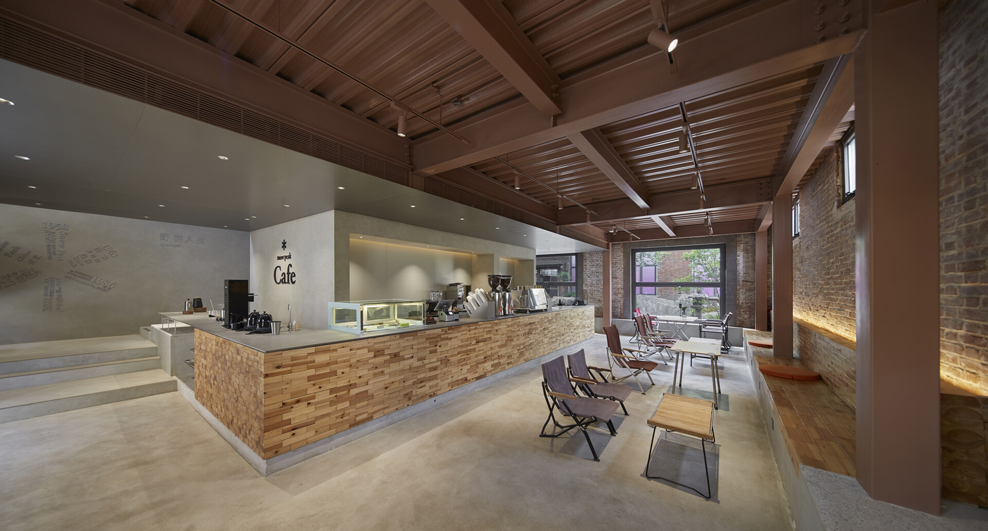 This renovated red-brick warehouse was transformed into a modern cafe, and the central feature is a large multi-functional bar that handles coffee service, retail display, and the checkout area.