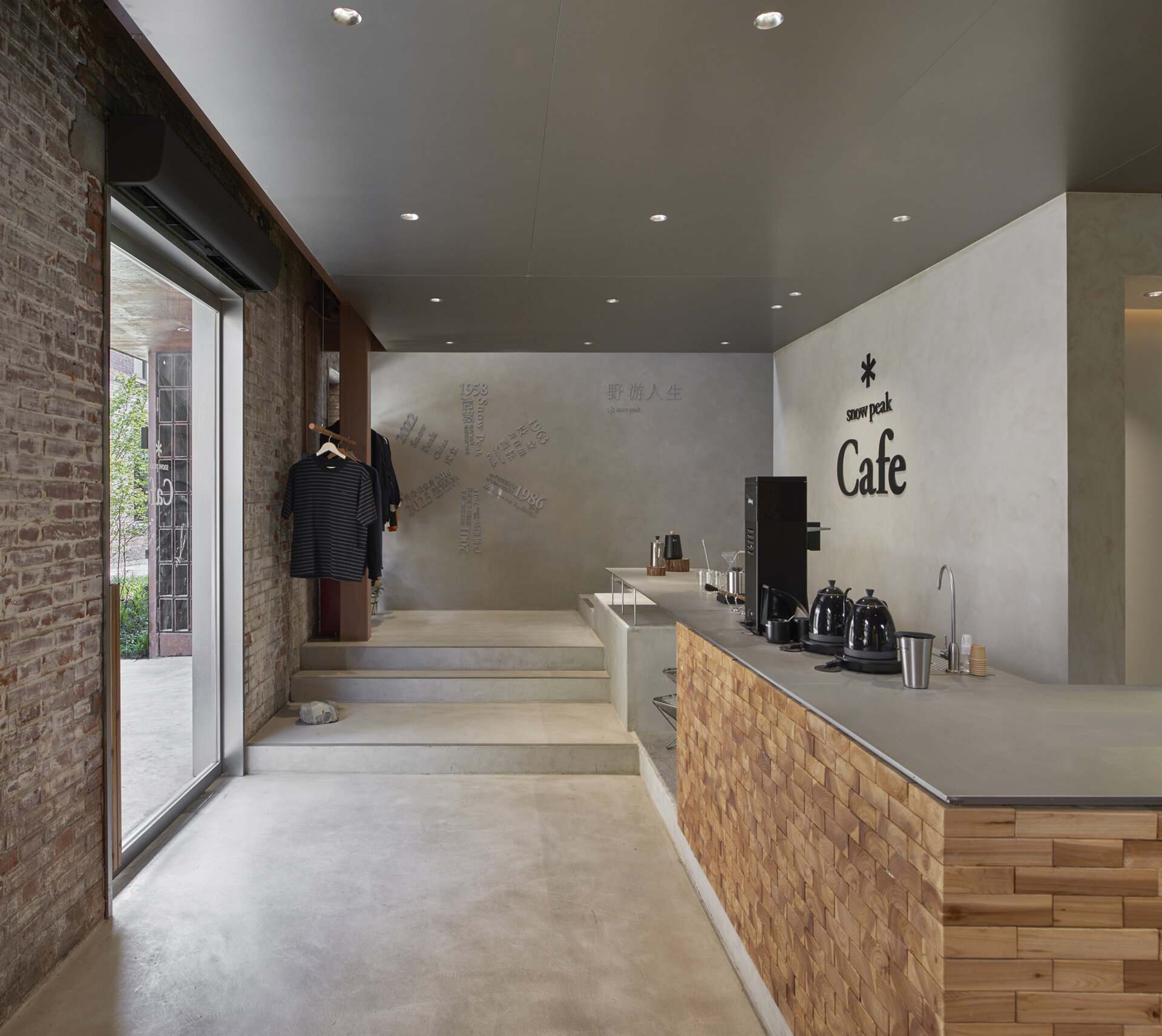 In this modern cafe, a staircase rises directly from the floor in a clean micro-cement form. It blends seamlessly with the bar and display area, and serves both as a functional element and a visual connector between floors.