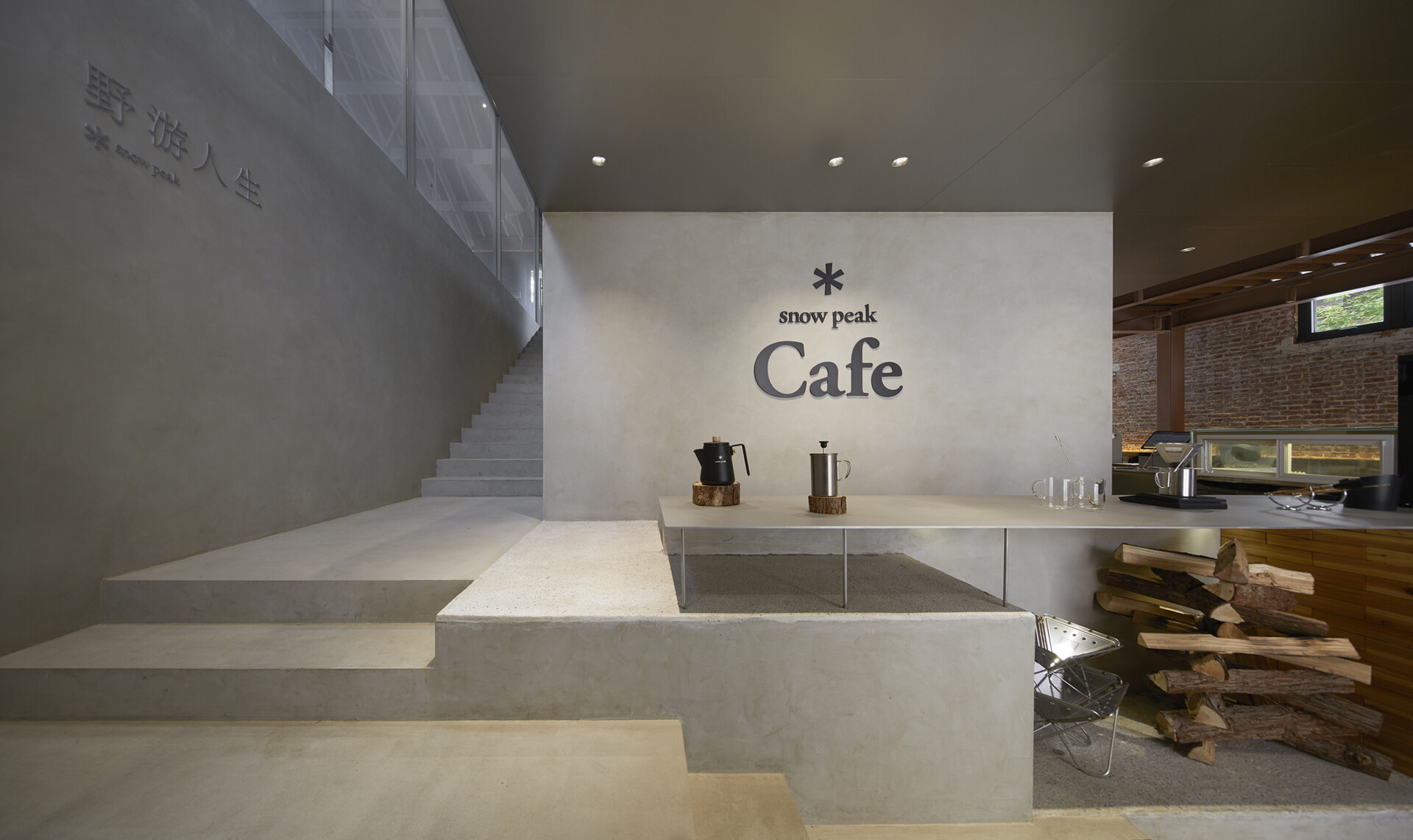 In this modern cafe, a staircase rises directly from the floor in a clean micro-cement form. It blends seamlessly with the bar and display area, and serves both as a functional element and a visual connector between floors.
