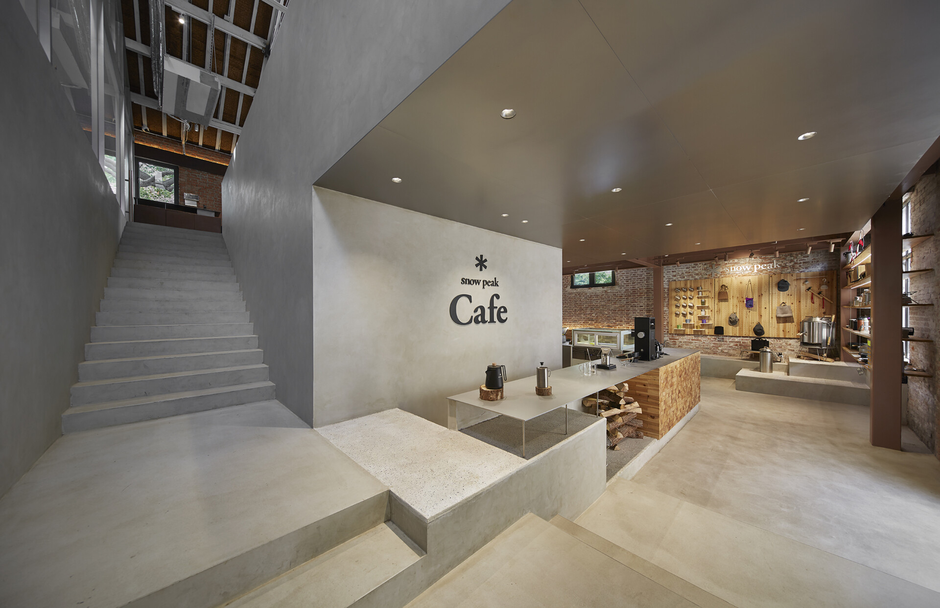 In this modern cafe, a staircase rises directly from the floor in a clean micro-cement form. It blends seamlessly with the bar and display area, and serves both as a functional element and a visual connector between floors.