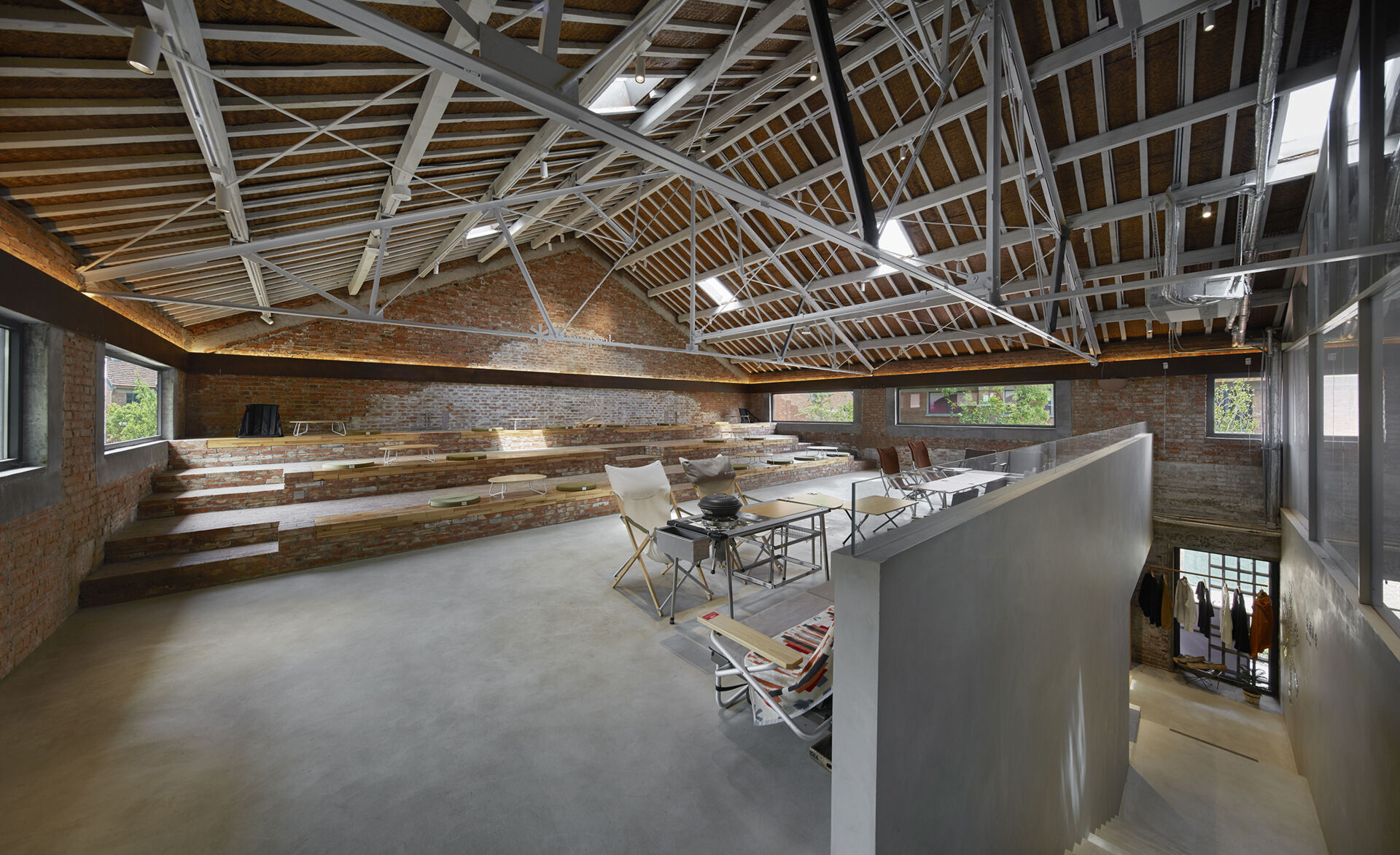 In a modern cafe located inside a renovated red-brick warehouse, there's two levels, with the upper level including stepped seating made from reclaimed brick.