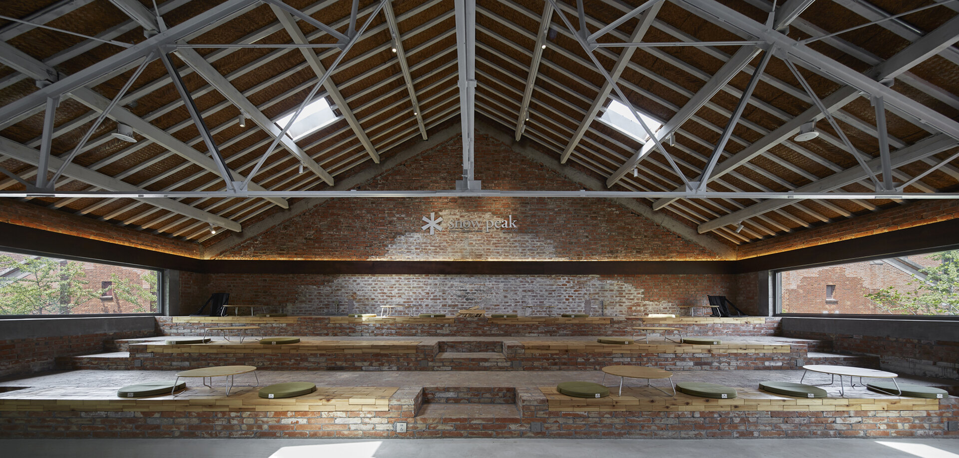 In a modern cafe located inside a renovated red-brick warehouse, there's two levels, with the upper level including stepped seating made from reclaimed brick.