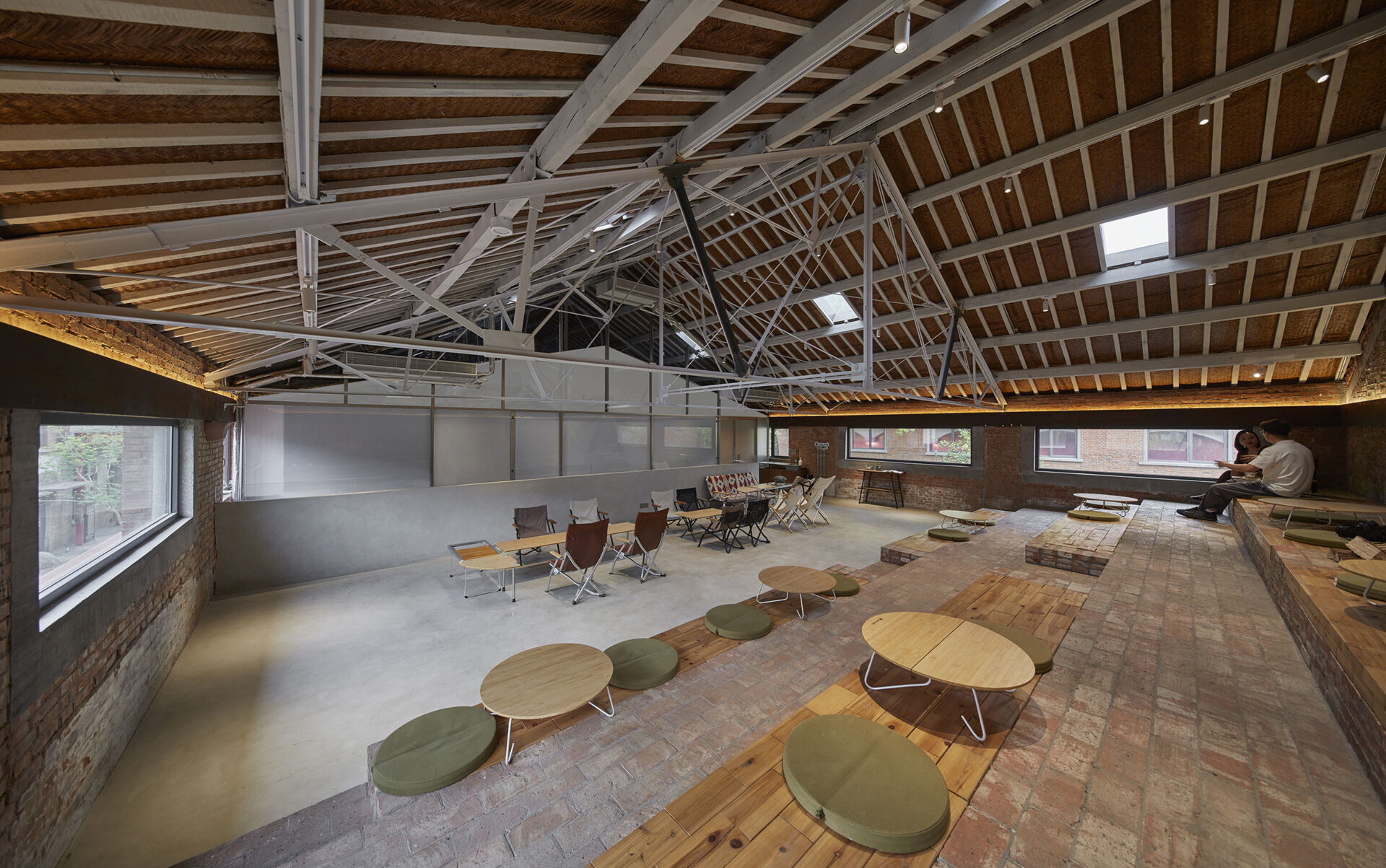 In a modern cafe located inside a renovated red-brick warehouse, there's two levels, with the upper level including stepped seating made from reclaimed brick.