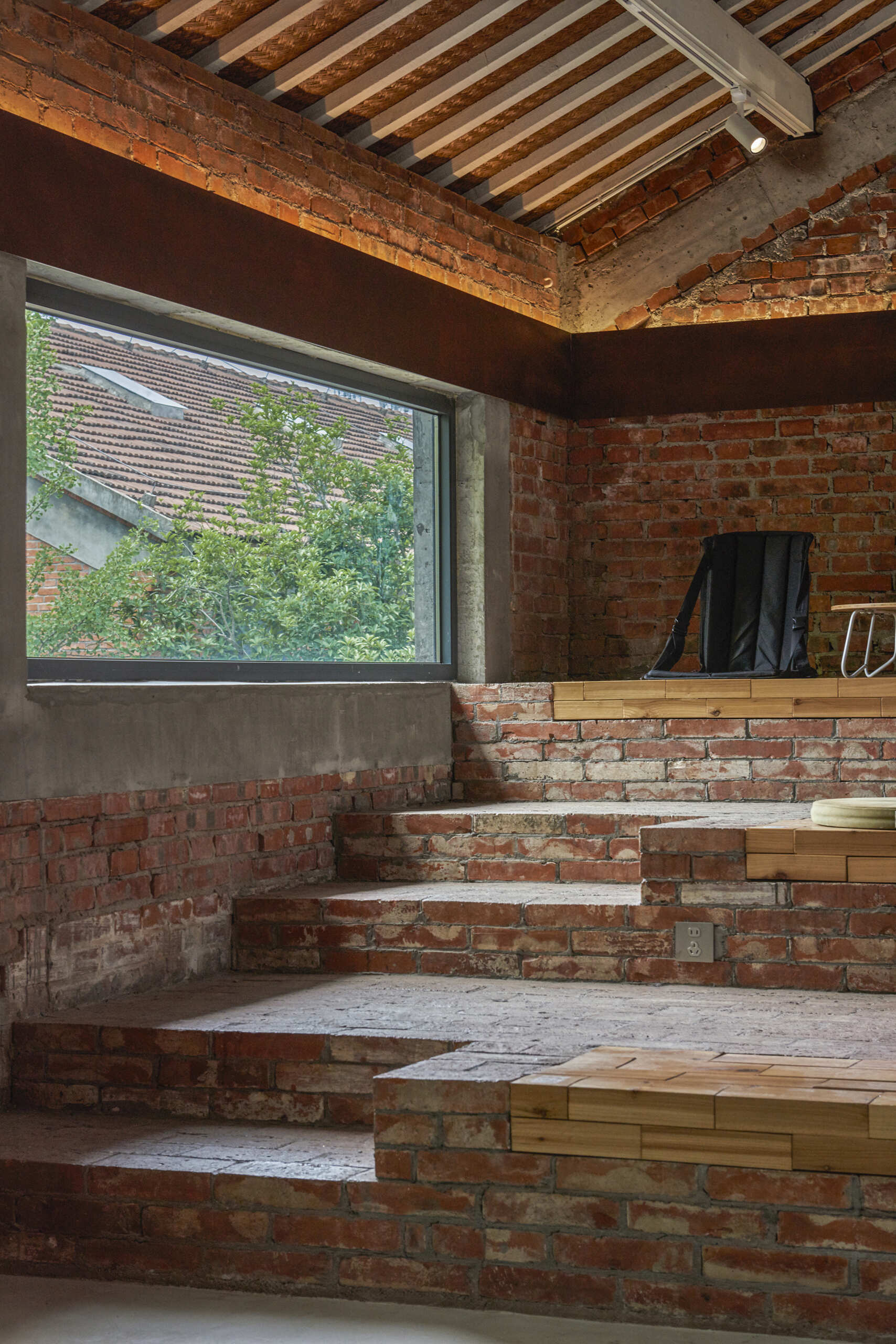 In a modern cafe located inside a renovated red-brick warehouse, there's two levels, with the upper level including stepped seating made from reclaimed brick.