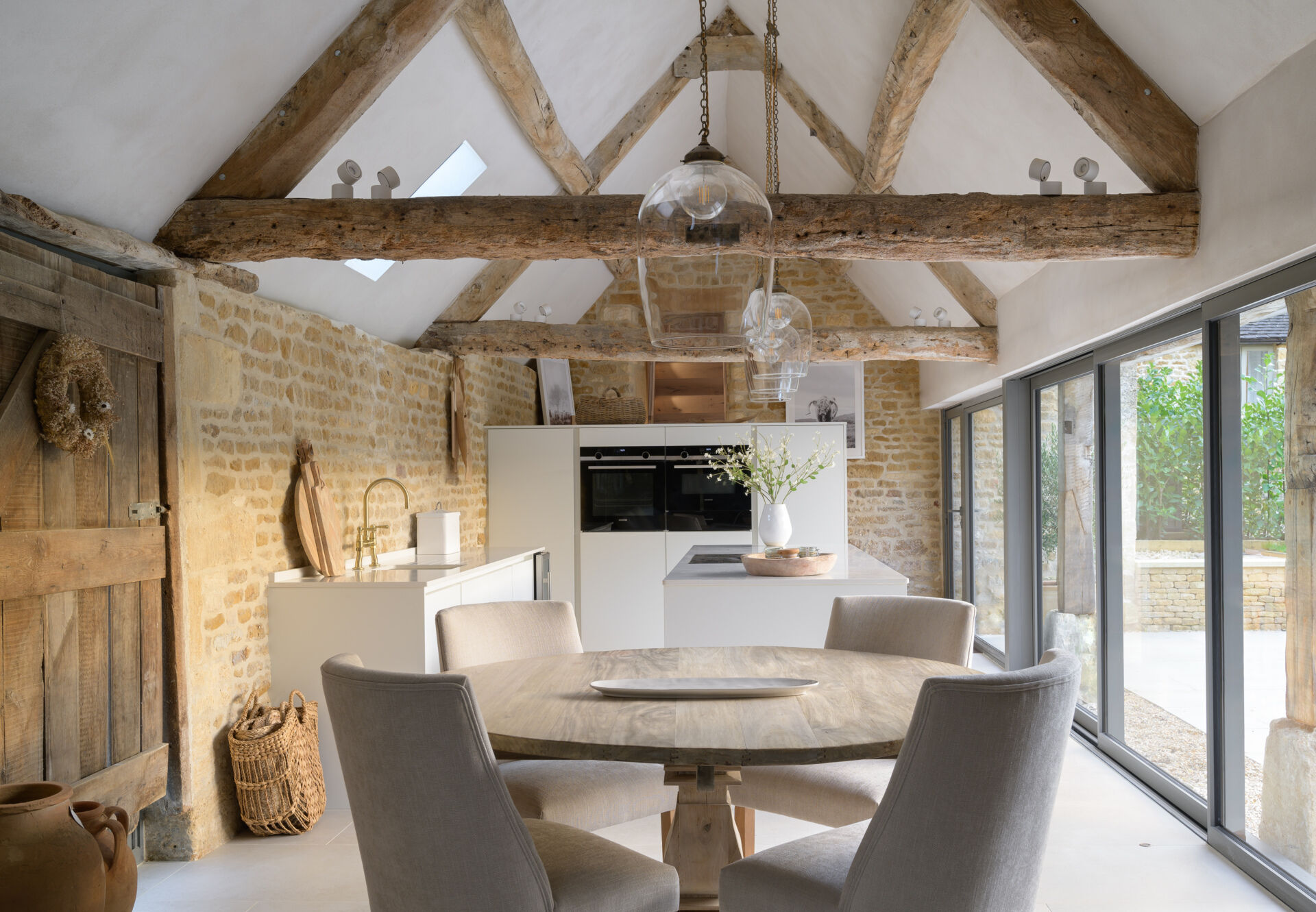 In this renovated cowshed, the dining area separates the living room and kitchen, which is designed to feel both functional and unfussy. Materials were kept simple and durable, aligning with the overall aesthetic. Timber detailing continues here, reinforcing the warm tones that run throughout the home. The layout allows for social cooking, without drawing attention away from the structure itself.