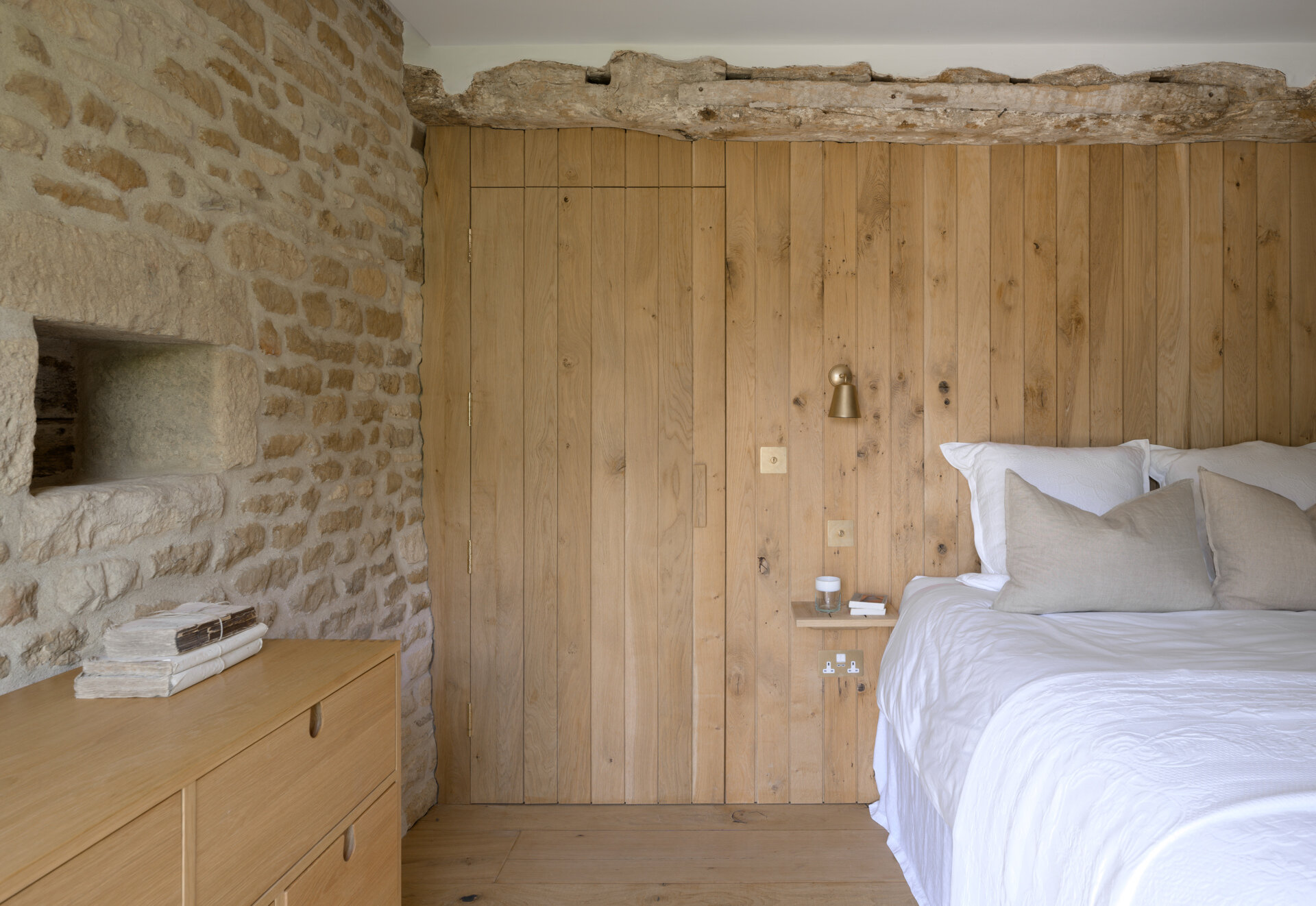 The guest bedroom is nestled into one side of the renovated barn, and is a simple, quiet space with a neutral palette, designed to feel both welcoming and private. Raw finishes and restrained styling keep the attention on the beautiful old structure.