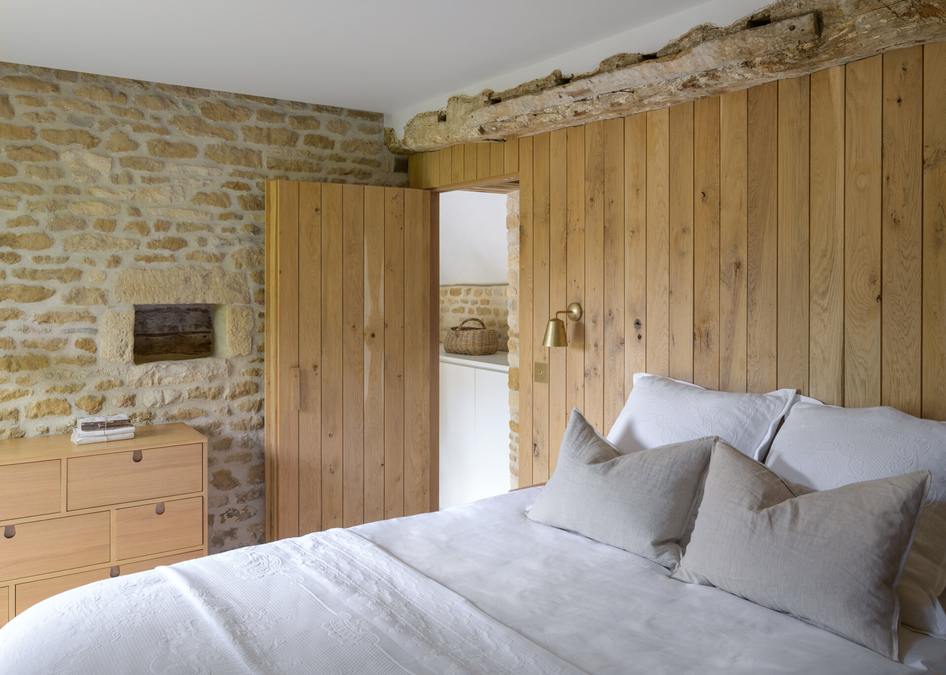 The guest bedroom is nestled into one side of the renovated barn, and is a simple, quiet space with a neutral palette, designed to feel both welcoming and private. Raw finishes and restrained styling keep the attention on the beautiful old structure.