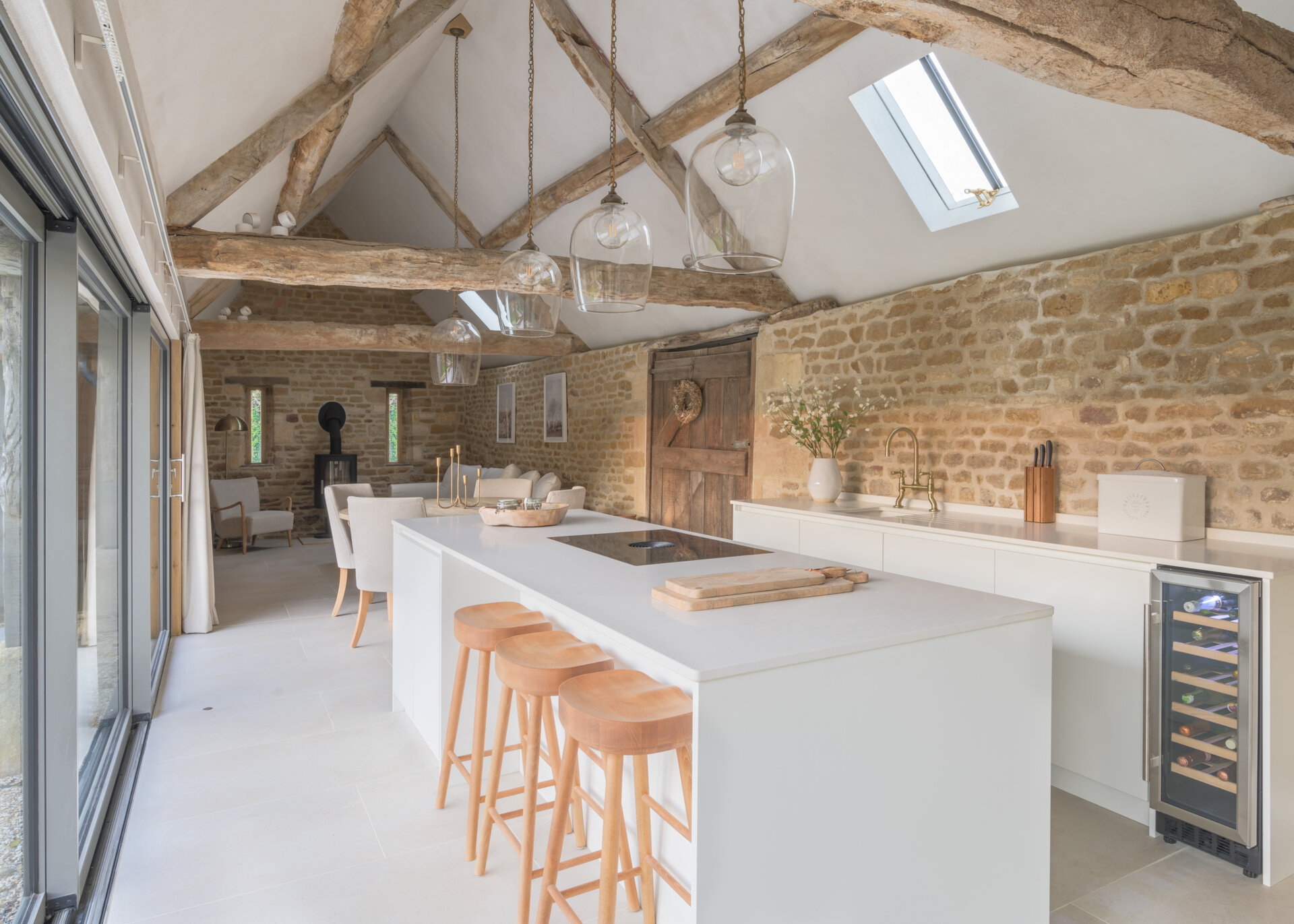 In this renovated cowshed, the dining area separates the living room and kitchen, which is designed to feel both functional and unfussy. Materials were kept simple and durable, aligning with the overall aesthetic. Timber detailing continues here, reinforcing the warm tones that run throughout the home. The layout allows for social cooking, without drawing attention away from the structure itself.