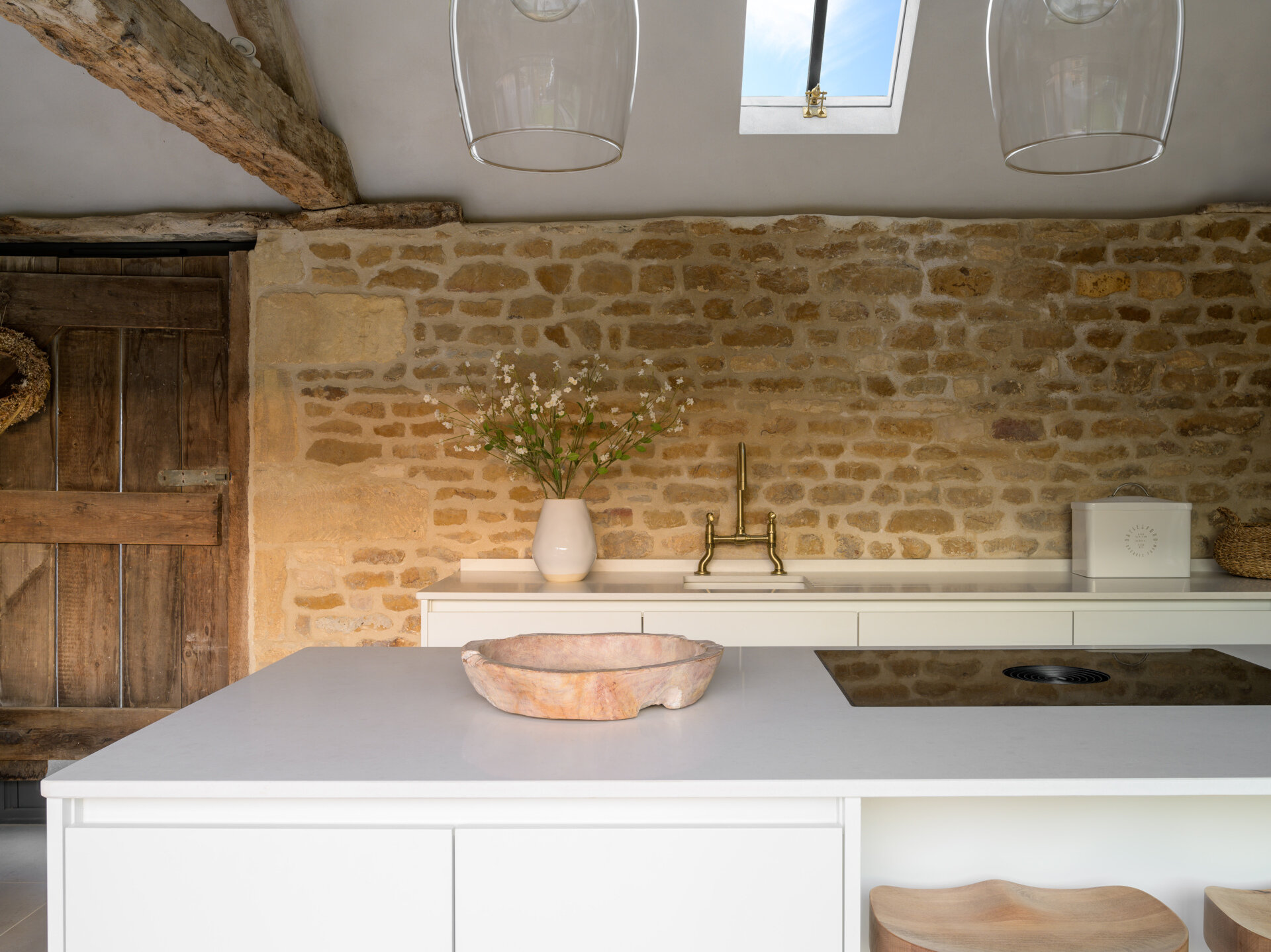 In this renovated cowshed, the dining area separates the living room and kitchen, which is designed to feel both functional and unfussy. Materials were kept simple and durable, aligning with the overall aesthetic. Timber detailing continues here, reinforcing the warm tones that run throughout the home. The layout allows for social cooking, without drawing attention away from the structure itself.